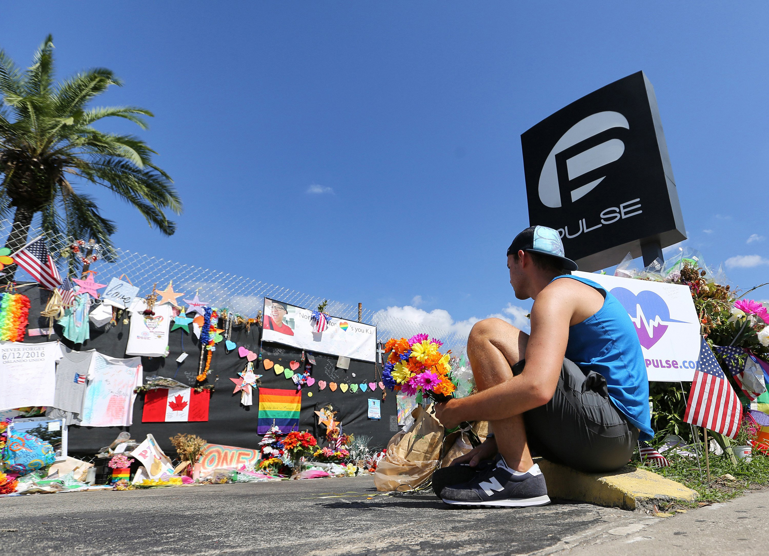 On the eve of the one-month anniversary of the Pulse nightclub massacre, a friend of two of the victims places flowers as visitors continue to flock to the club to their pay their respects in Orlando on July 11, 2016. (Joe Burbank—Zuma Press)