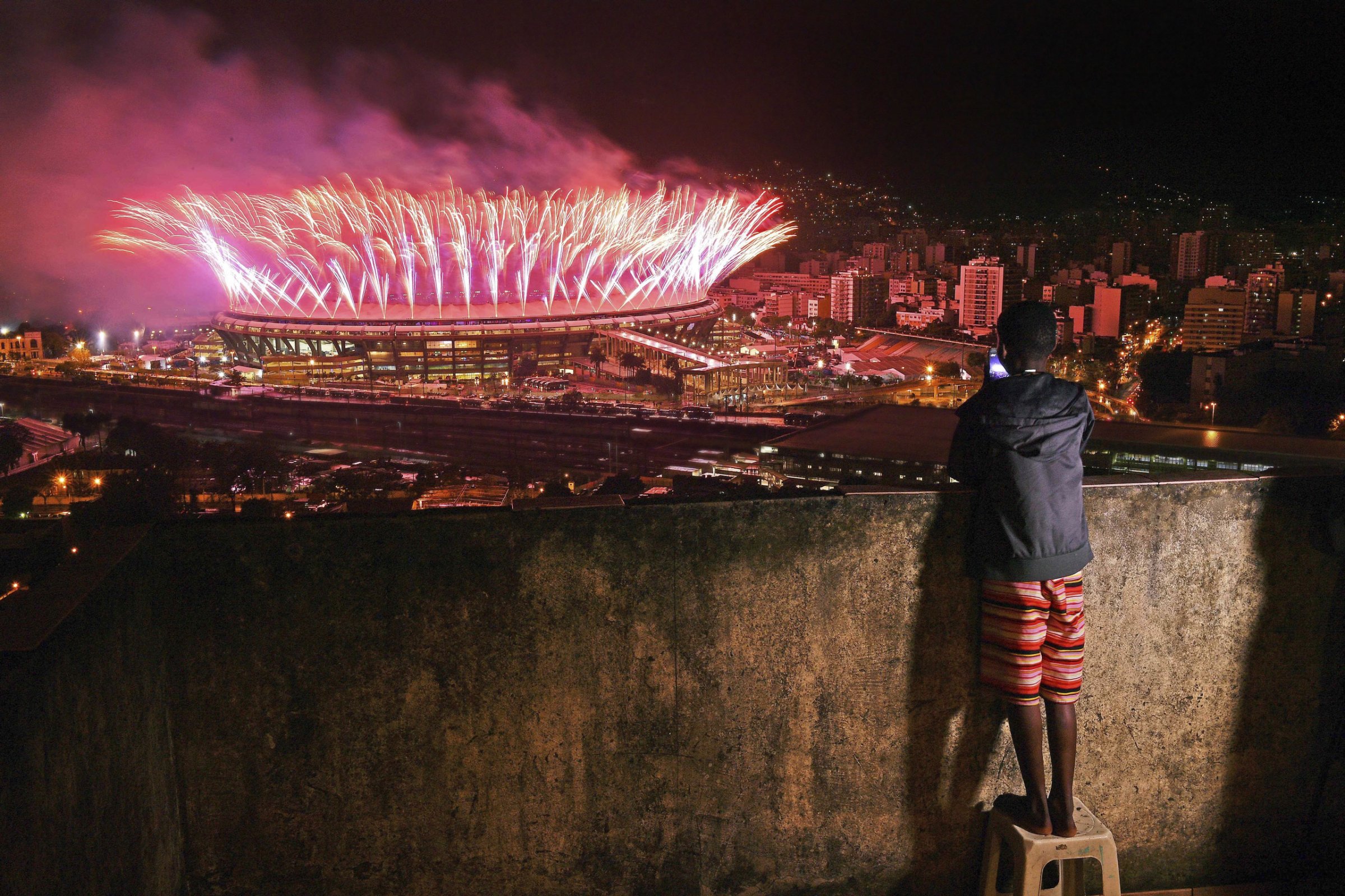 A boy watches the closing ceremony of the Rio Olympics from the Mangueira favela on Aug. 21
