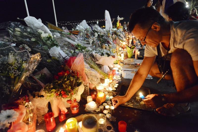 A man places candles near flowers that were left in tribute at makeshift memorials to the victims of the truck attack along the Promenade des Anglais in Nice, France, July 18, 2016 (Jean-Pierre Amet—Reuters)