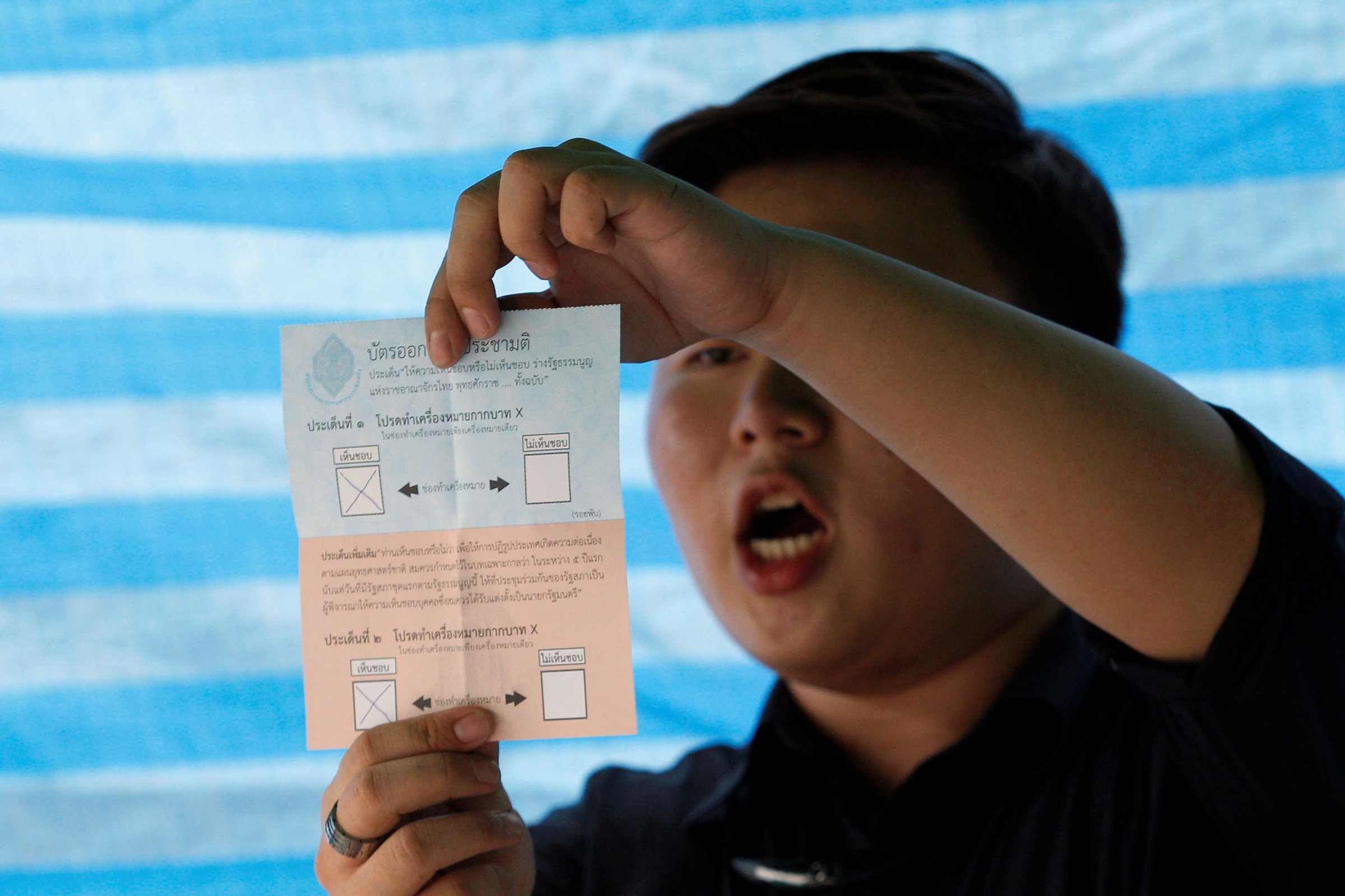 A Thai electoral worker starts counting ballots at a polling station during a constitutional referendum vote in Bangkok