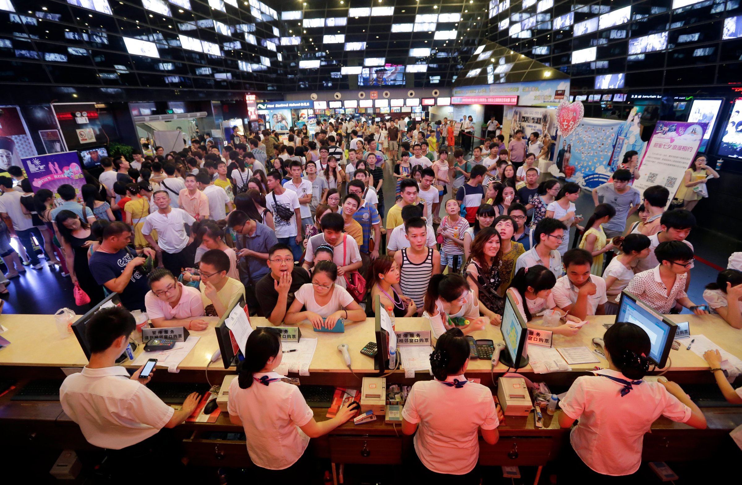 People wait for tickets at a ticket office of a movie theatre in Wuhan