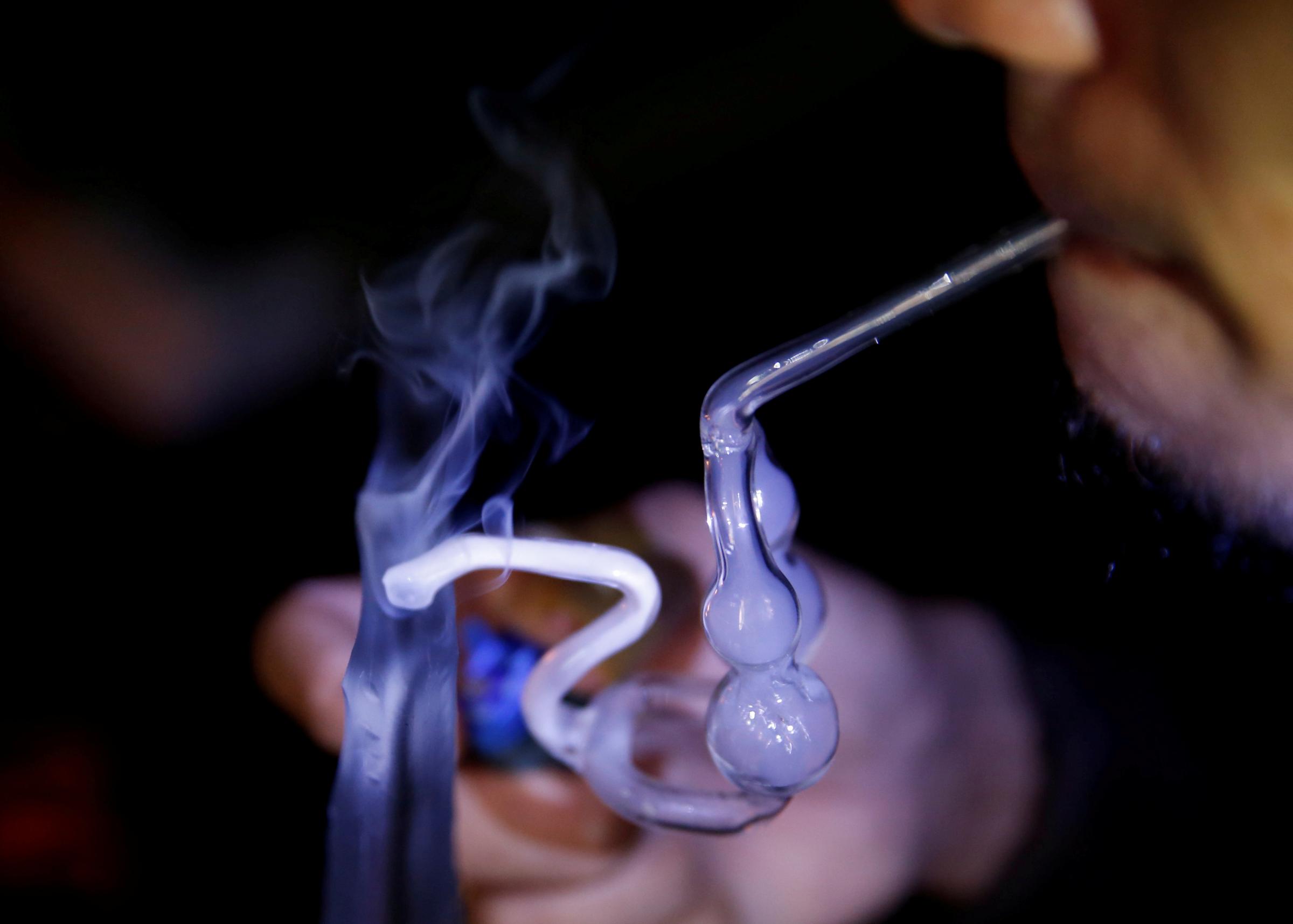 A drug addict uses a glass water pipe to smoke shabu at an undisclosed drug den in Manila
