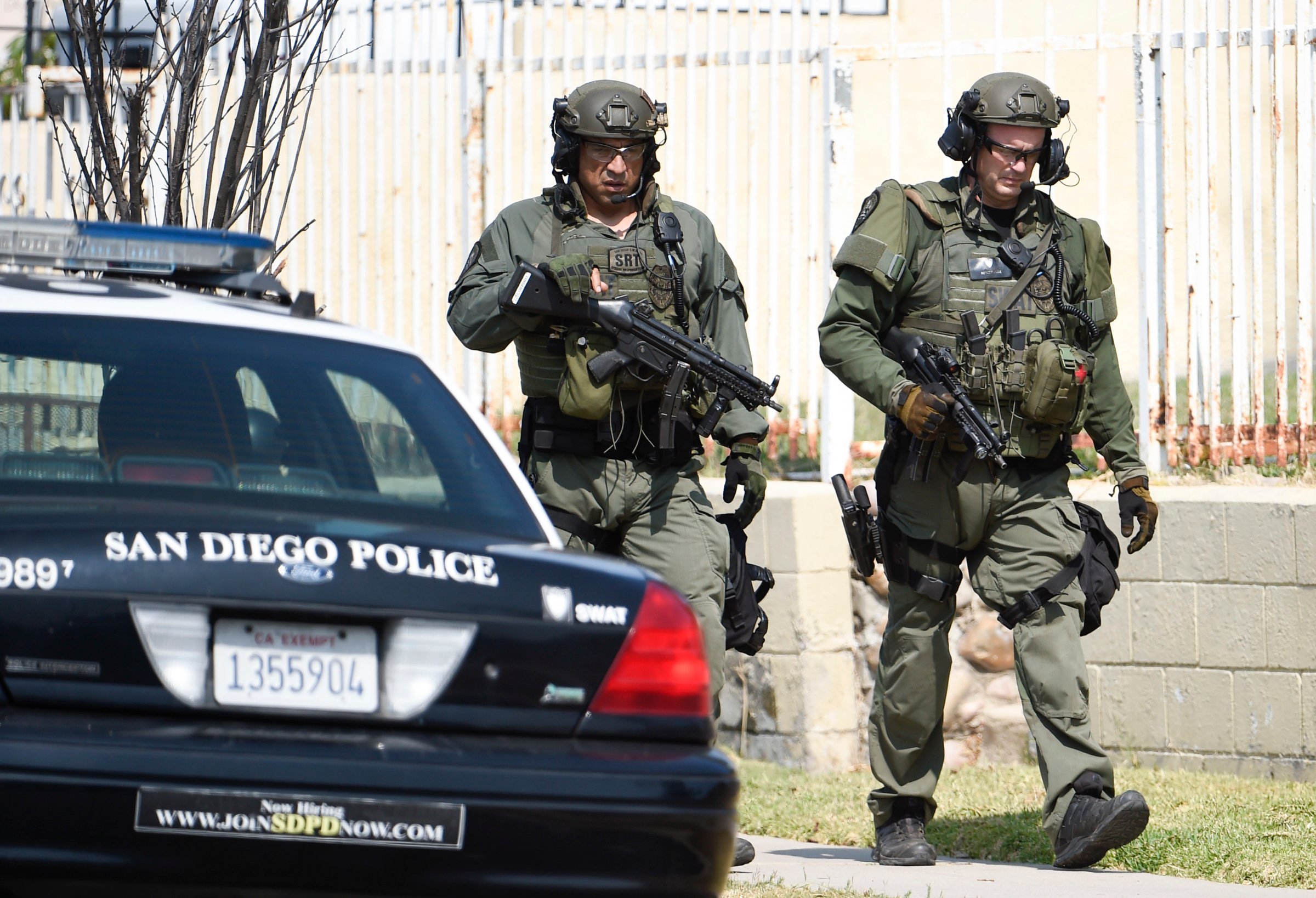 San Diego Police SWAT officers walk down the street after entering a house with a possible suspect inside, on July 29, 2016, in San Diego.
