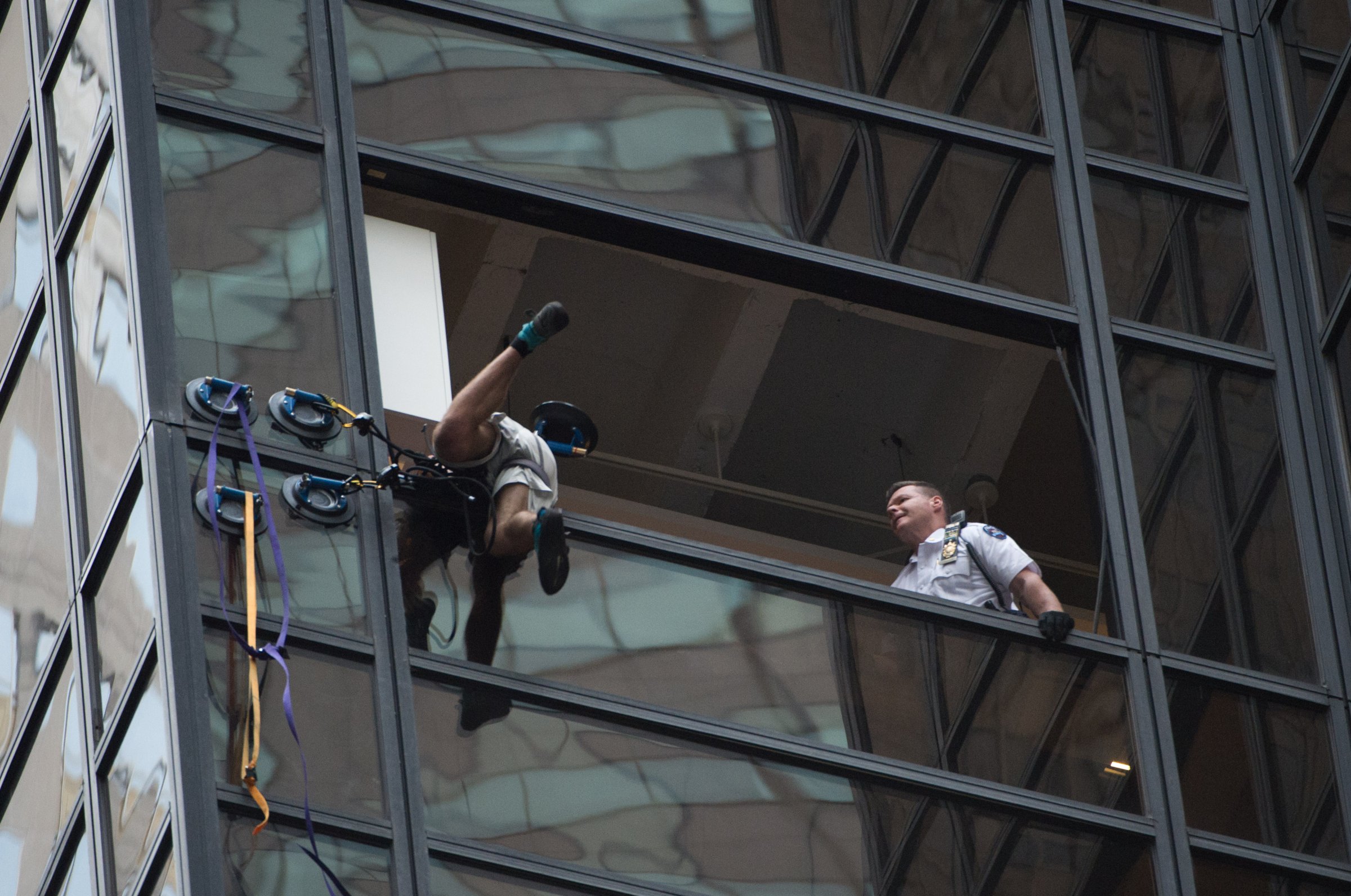 Police grab an unidentified man scaling Trump Tower using suction cups, August 10, 2016 in New York. Police on August 10, 2016 captured a climber scaling Trump Tower, dragging him to safety through an open window on the 21st floor of the New York headquarters of the Republican nominee for US president. Live television footage showed uniformed officers reaching out and grabbing the young man -- dressed in grey shorts, an olive T-shirt and white cap -- around three hours after he started his ascent using five suction cups. "The climber has been taken into custody," a police spokesman tweeted.