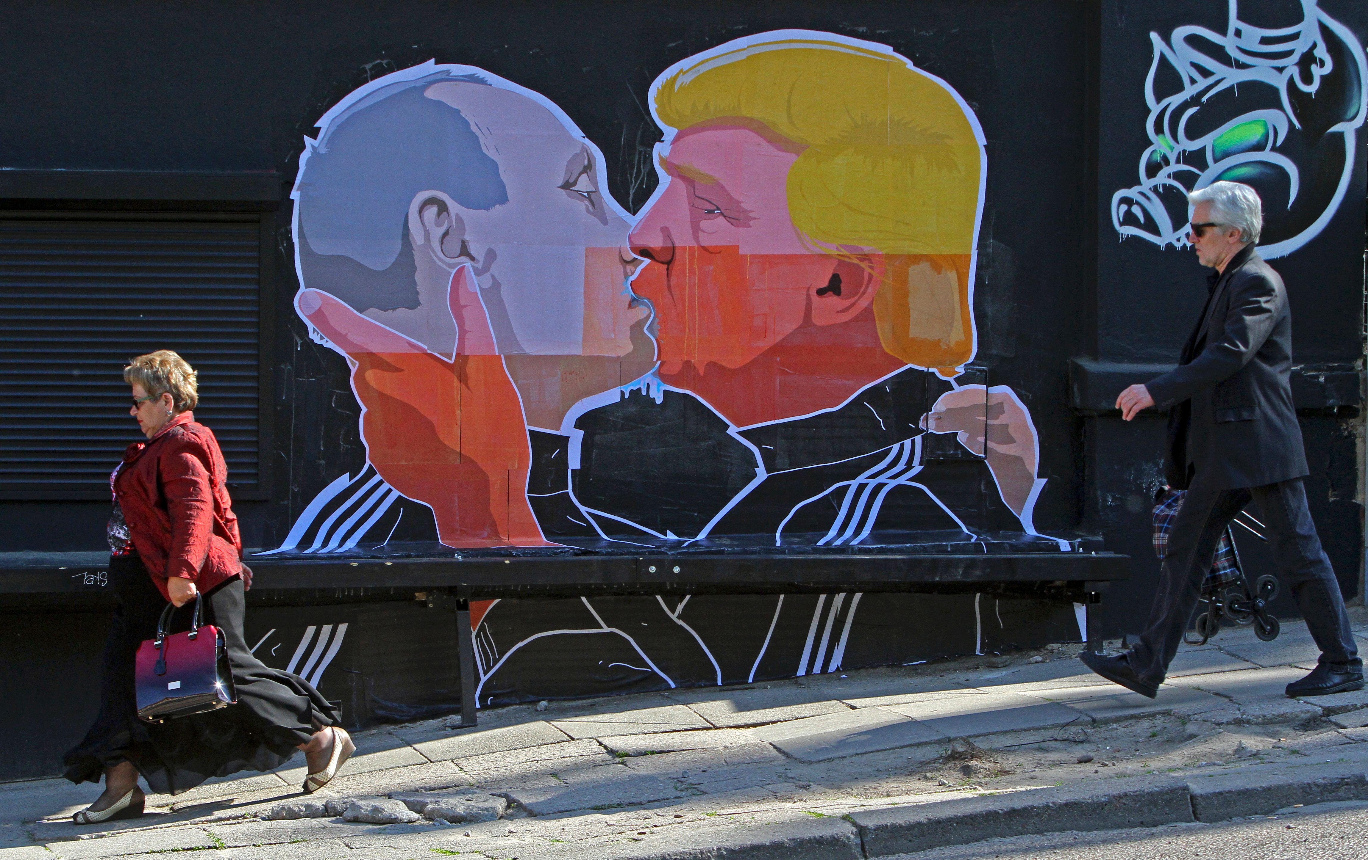 People walk past a mural on a restaurant wall depicting U.S.  Presidential hopeful Donald Trump and Russian President Vladimir Putin greeting each other with a kiss in the Lithuanian capital Vilnius on May 13, 2016.