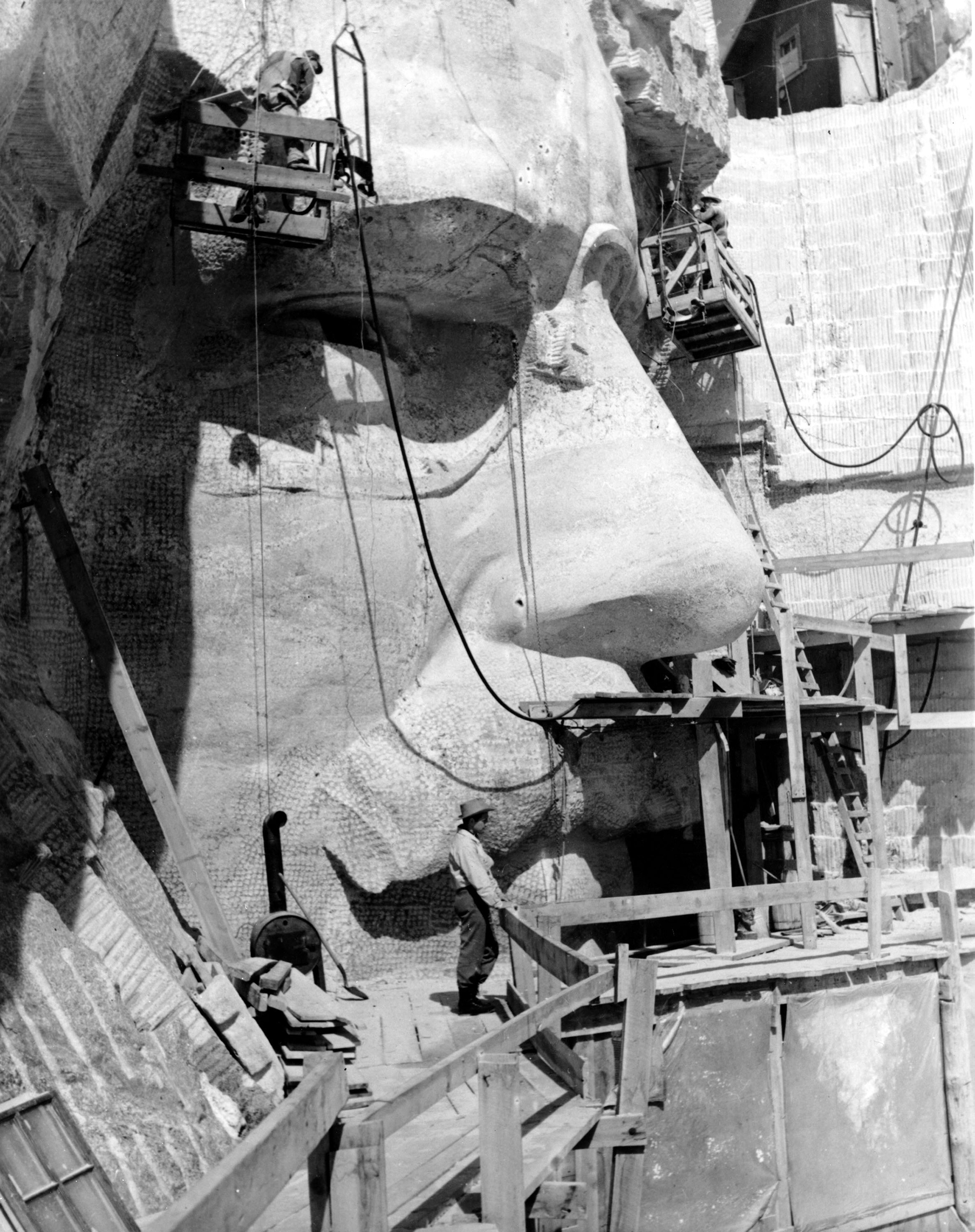 Sculptor Lincoln Borglum on the scaffold below the stone face of U.S. President Theodore Roosevelt on the Mount Rushmore Memorial in April 1944.