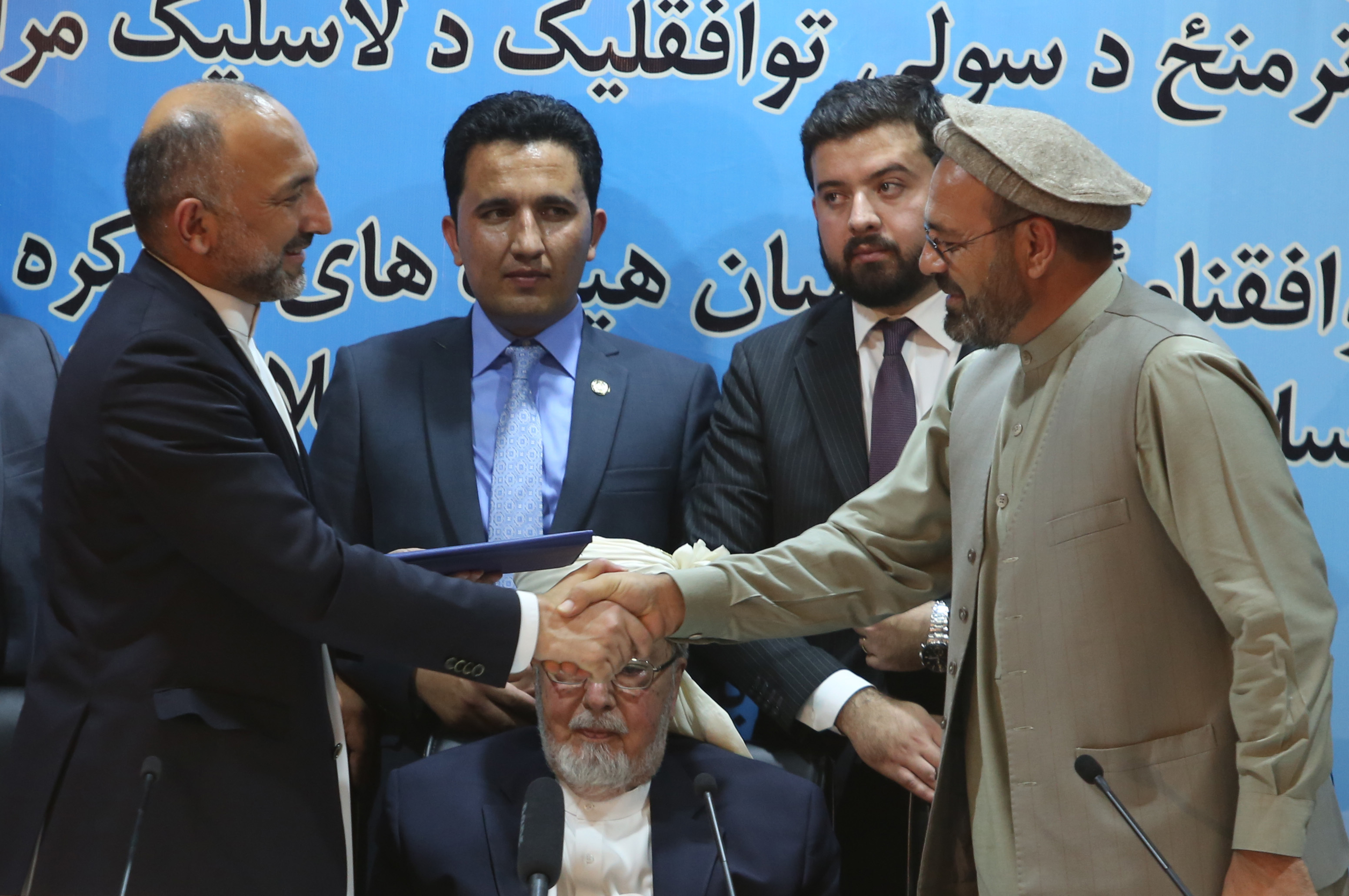Afghanistan national security adviser Mohammad Hanif Atmar, left, and Amin Karim, representative of Gulbuddin Hekmatyar, right, shake hands after signing a peace deal in Kabul, Afghanistan, Thursday, Sept. 22, 2016. (Rahmat Gul—AP)