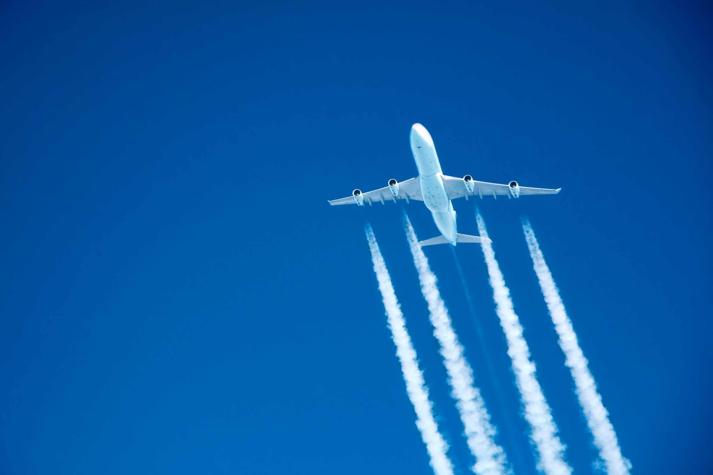 contrails streaming from a jumbo jet on blue sky at altitude