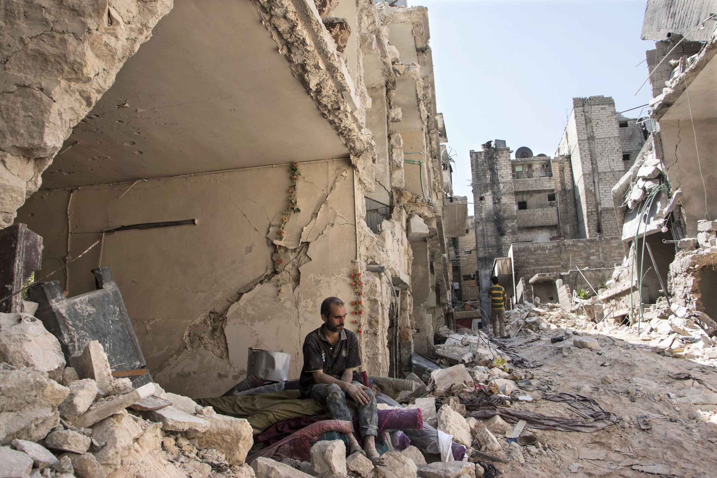 A Syrian man sits in the rubble following a barrel bomb attack the previous day on the rebel-held neighborhood of al-Mashad in Aleppo on Sept. 17, 2015.