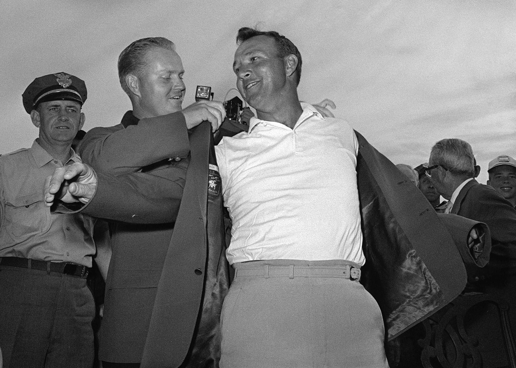 Arnold Palmer, right, slips into his green jacket with help from Jack Nicklaus after winning the Masters golf championship, in Augusta, Ga, April 12, 1964.