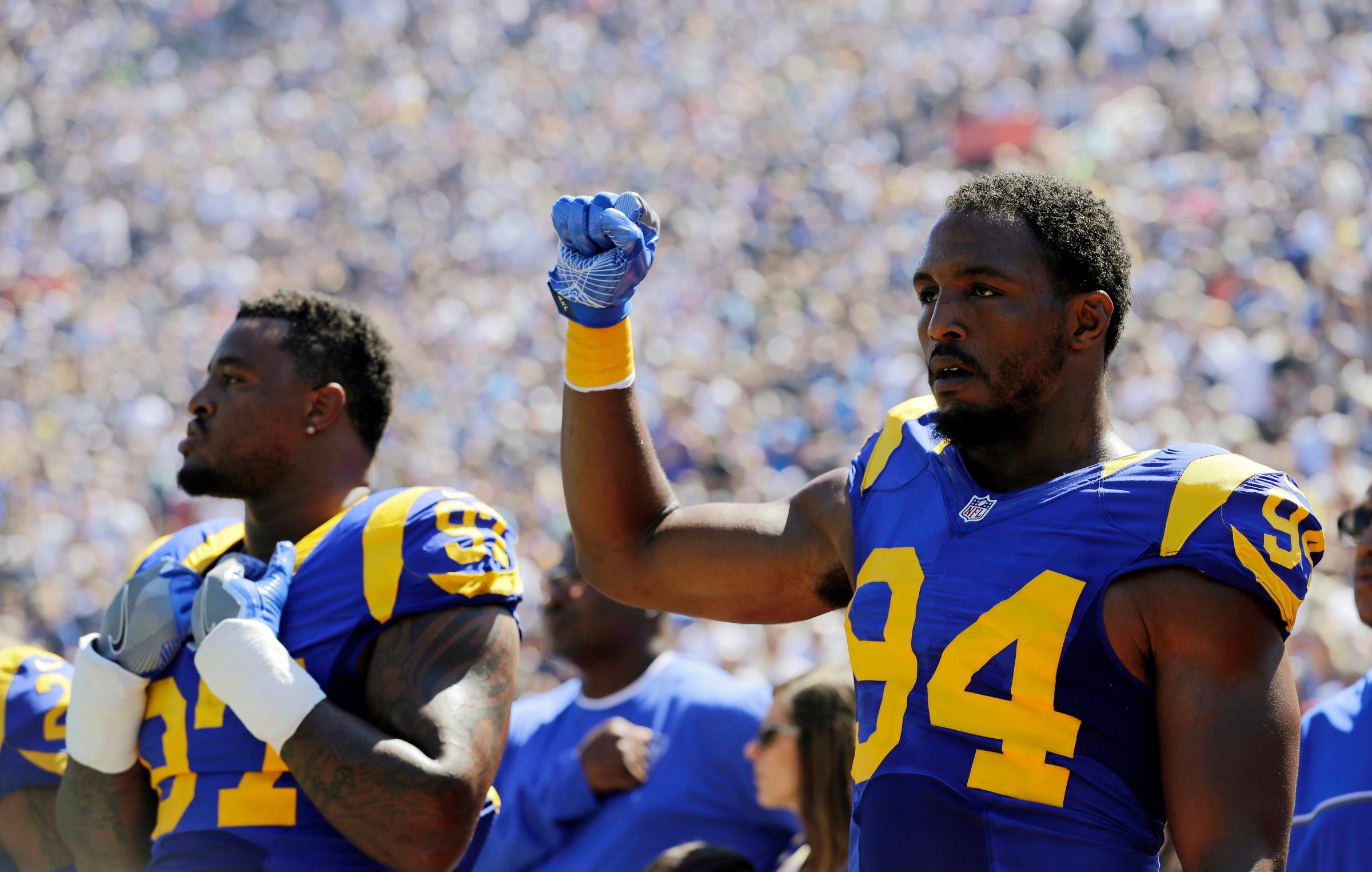 Los Angeles Rams defensive end Robert Quinn, right, raises his fist during the national anthem prior to an NFL football game against the Seattle Seahawks at Los Angeles Memorial Coliseum in Los Angeles, Sept. 18, 2016.