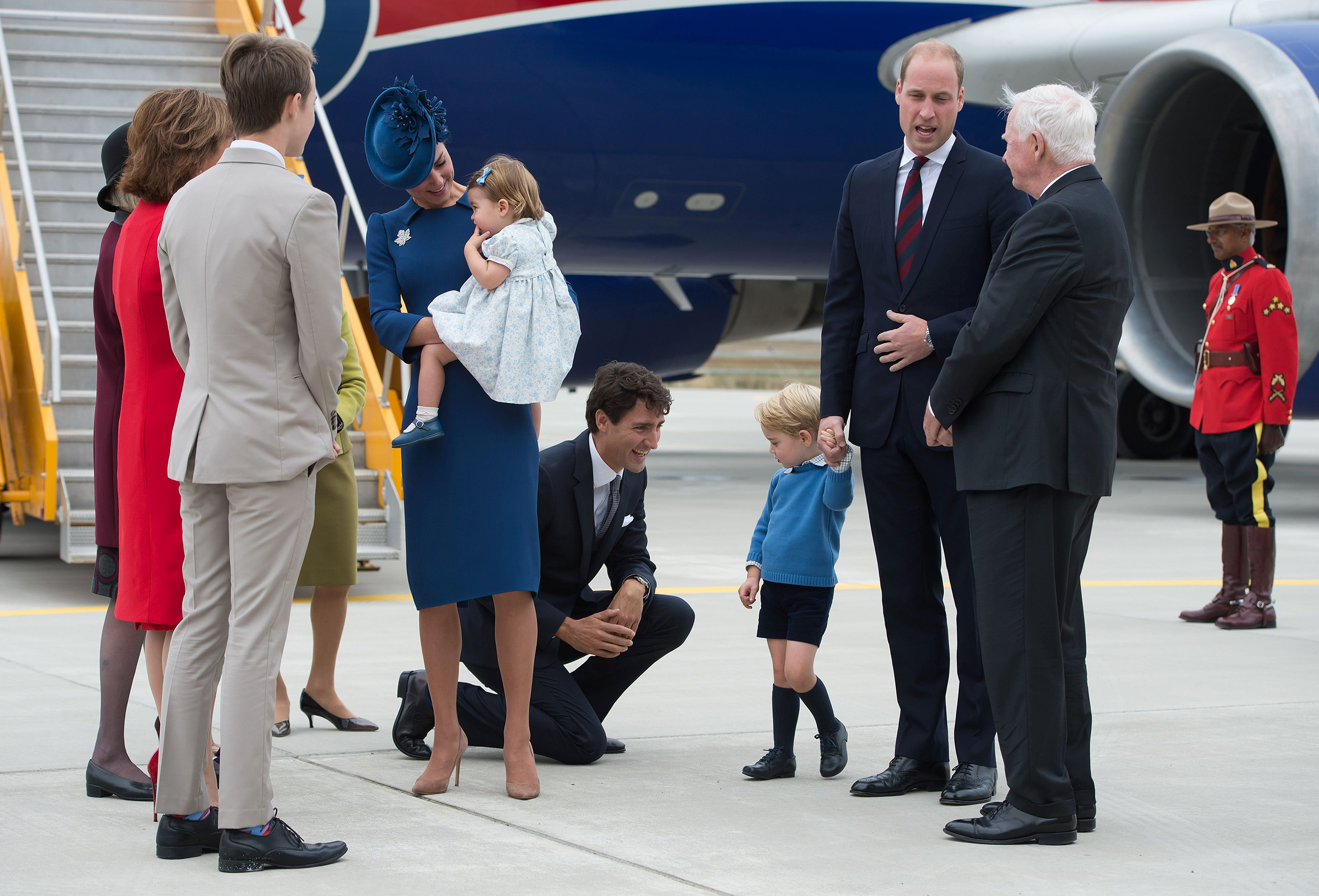 Canadian Prime Minister Justin Trudeau kneels to talk to Prince George as his father Prince William, The Duke of Cambridge, speaks with the Governor General David Johnston and Catherine, The Duchess of Cambridge, holds their daughter Princess Charlotte upon arrival at 443 Maritime Helicopter Squadron base on in Victoria, British Columbia, Sept. 24, 2016.