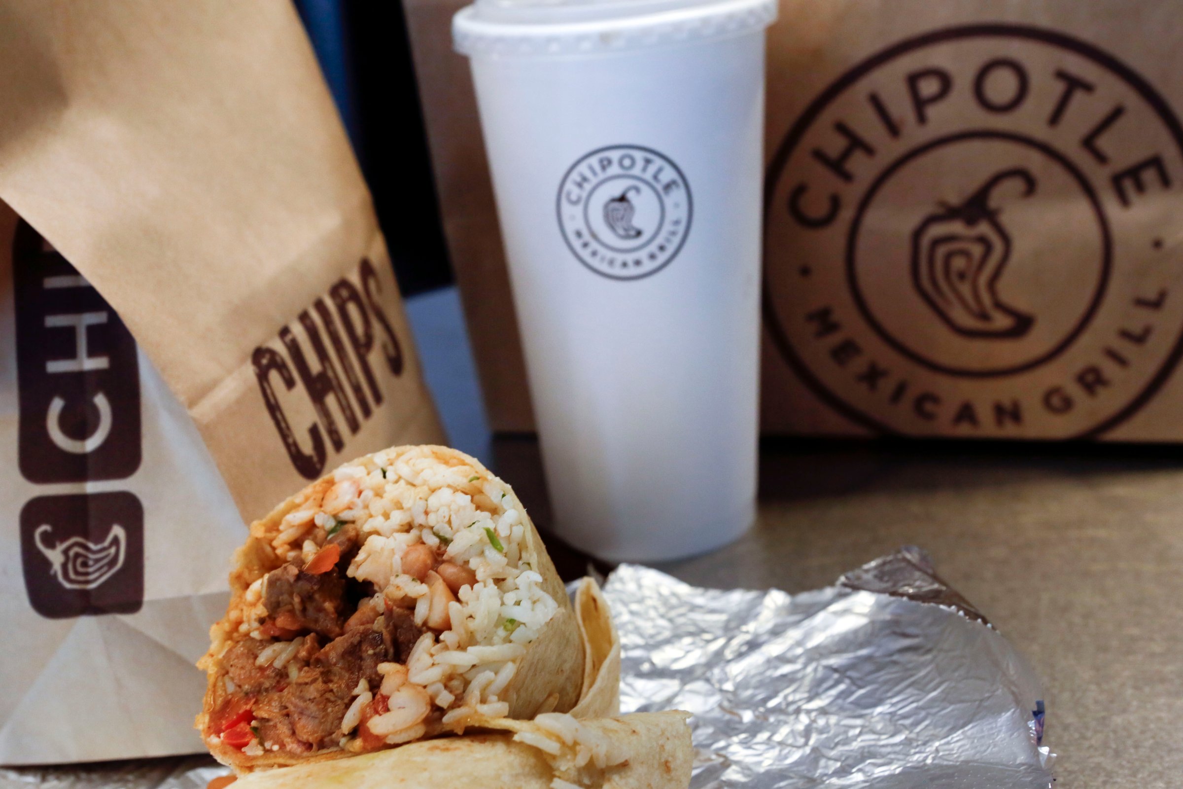 A steak burrito is arranged for a photograph with a drink and bags of chips at a Chipotle Mexican Grill Inc. restaurant in Hollywood, California, U.S., on Tuesday, July 16, 2013.