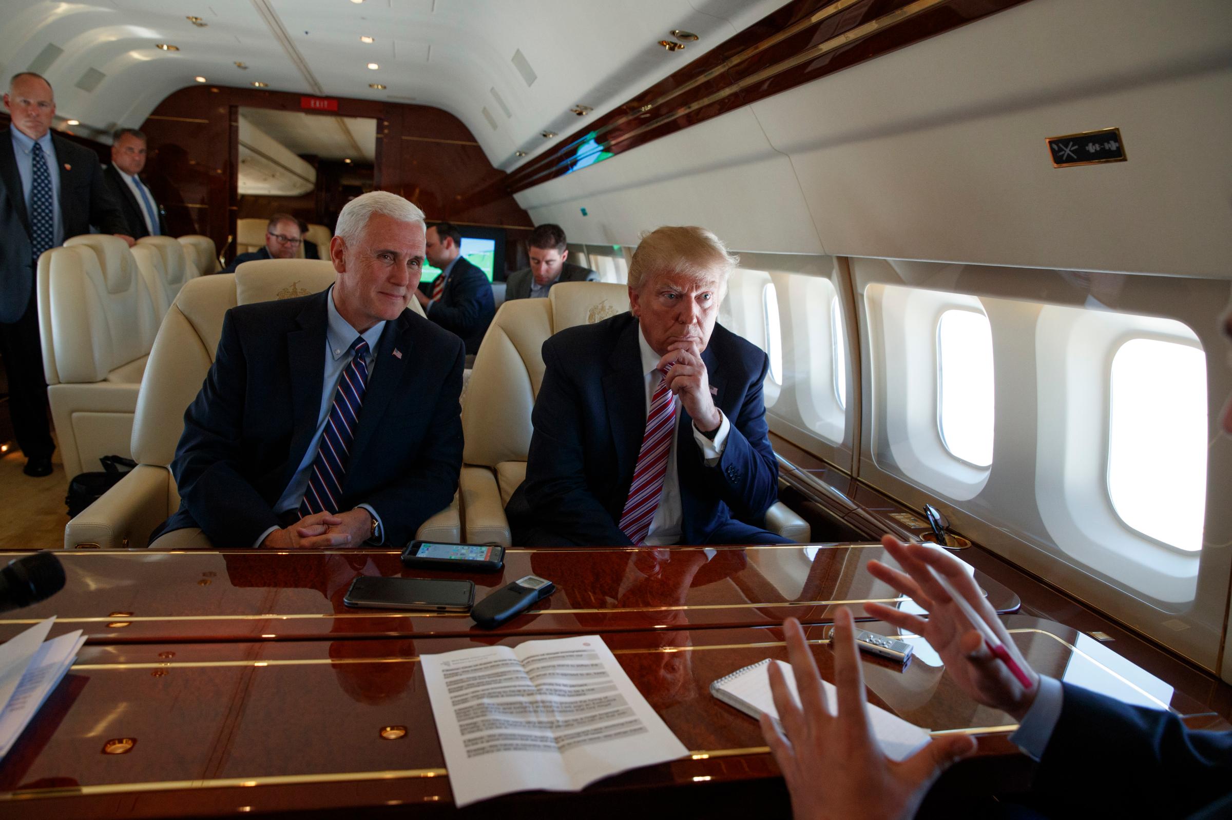 Republican presidential candidate Donald Trump talks with press, Sept. 5, 2016, aboard his campaign plane while flying over Ohio, as Vice presidential candidate Gov. Mike Pence, R-Ind., left, looks on.