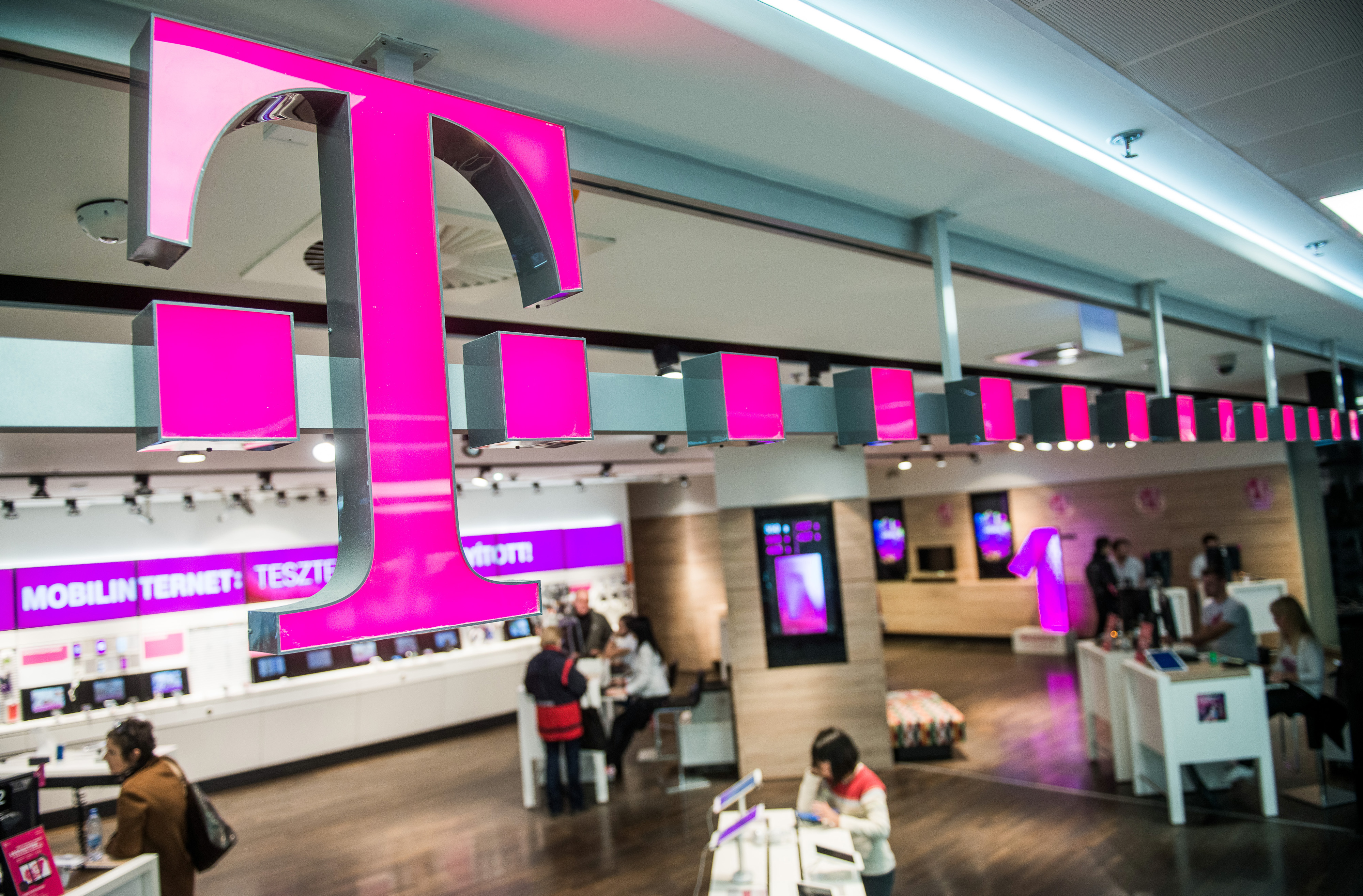 Customers browse mobile phone handsets as a sign sits above the entrance to a T-Mobile store, operated by Magyar Telekom Nyrt., in Budapest, Hungary, on Monday, Nov. 2, 2015. (Bloomberg&mdash;Bloomberg via Getty Images)