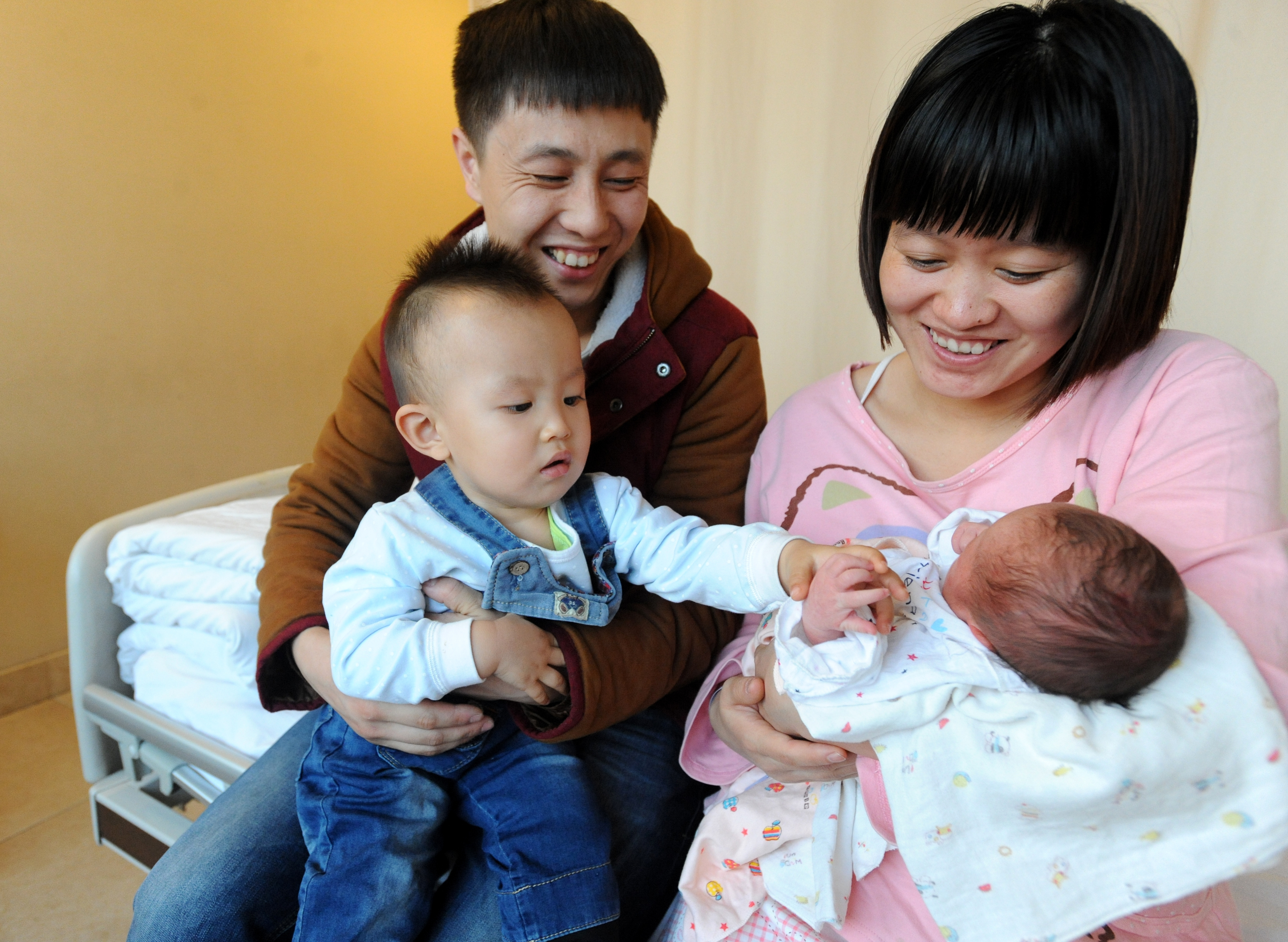 A couple smile as they look on their second child who was born at midnight on Jan. 1 at a hospital on Jan. 3, 2016, in Shenyang, China's Liaoning province. China has abandoned its 35-year-old one-child policy and started to allow all couples to have two children from Jan. 1, 2016, the Chinese Communist Party announced after a key meeting (VCG/Getty Images)