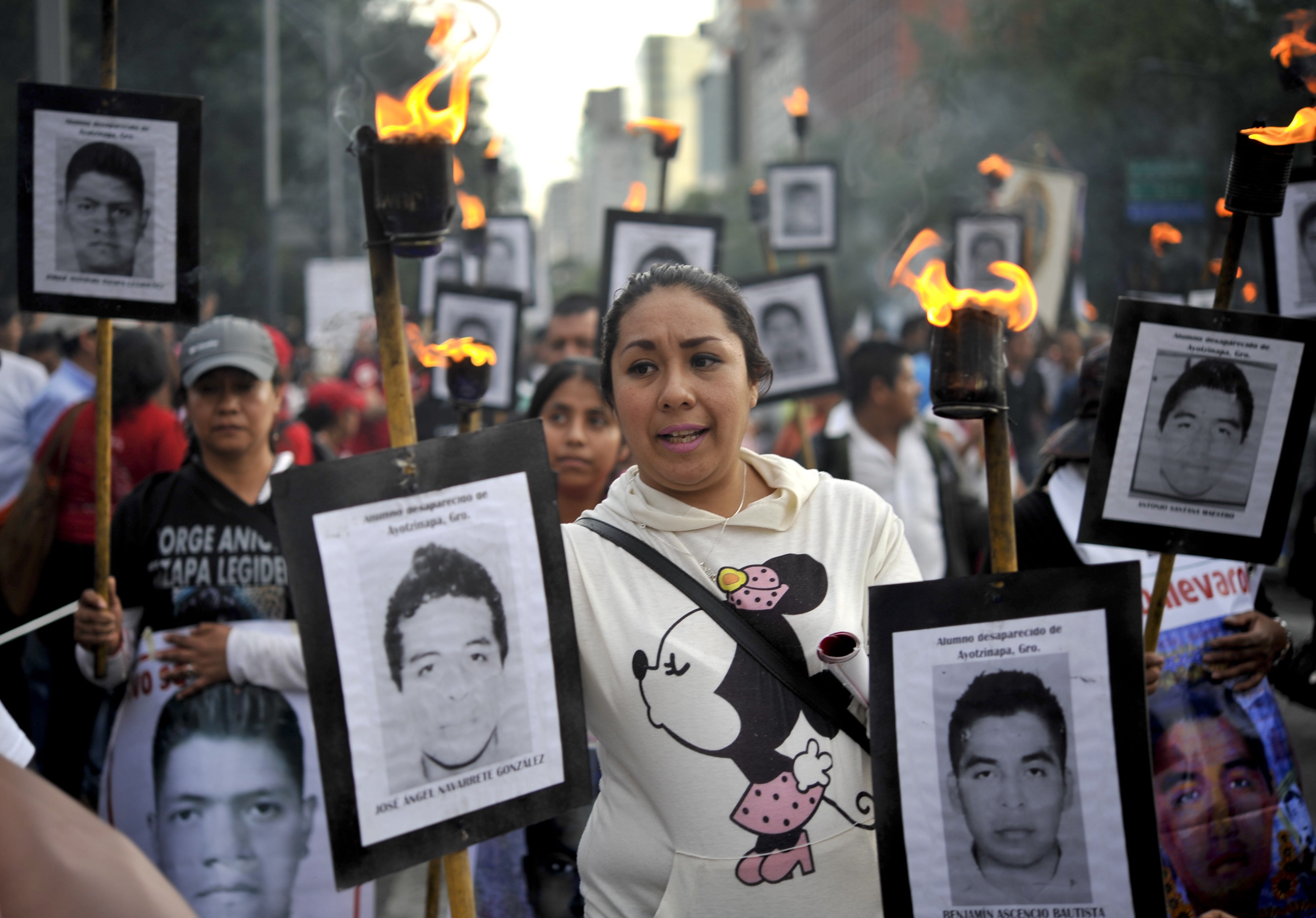 The parents of 43 missing students from Ayotzinapa teachers school hold their portraits and torches during a march 18 months after their disappearance in Mexico City on April 26, 2016. (YURI CORTEZ—AFP/Getty Images)