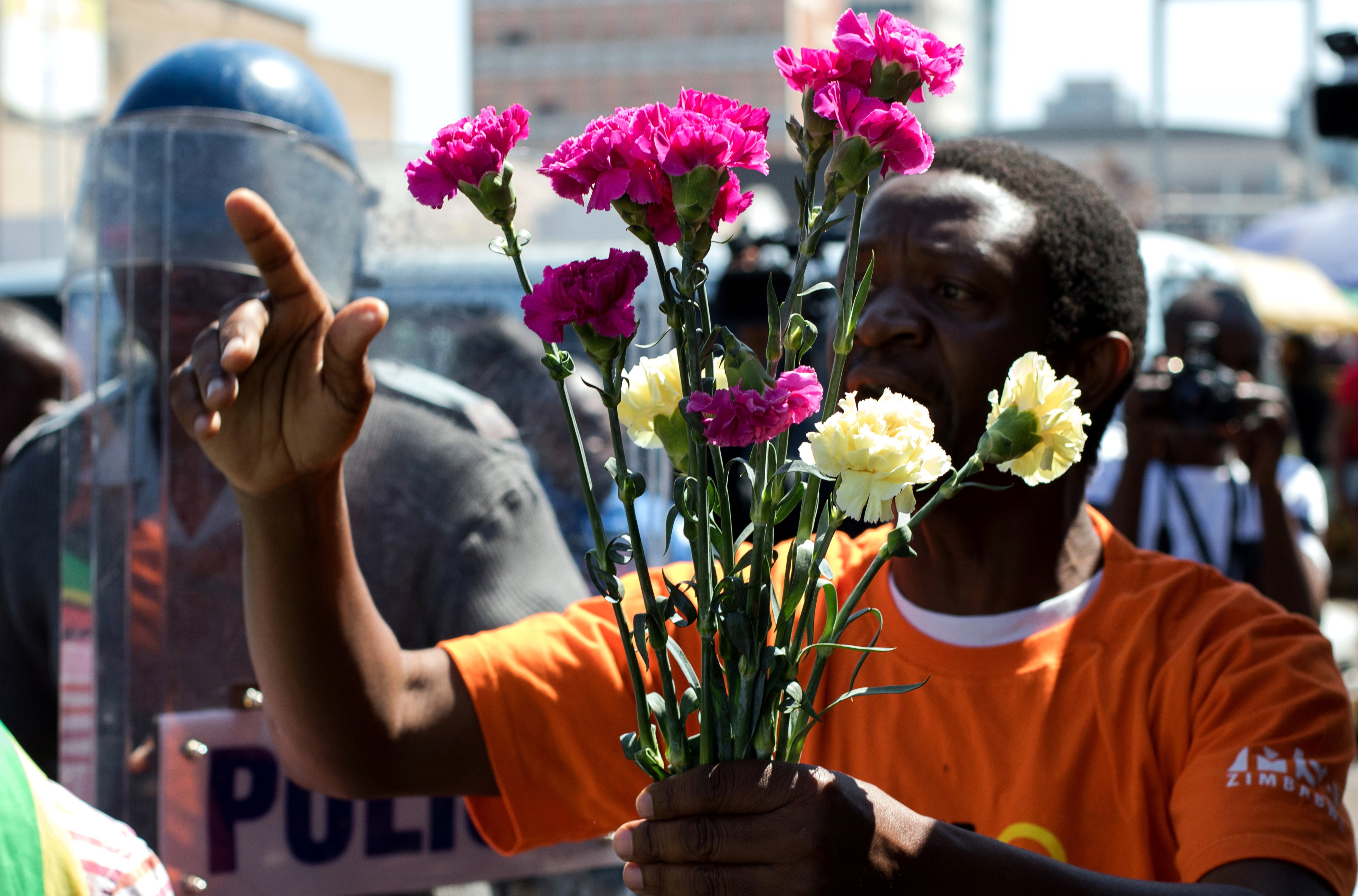 Zimbabwe activist Stan Zvorwadza offers flowers to antiriot policemen at Harare Central Police Station during a protest action on Aug. 18, 2016 (Jekesai Njikizana—AFP / Getty Images)