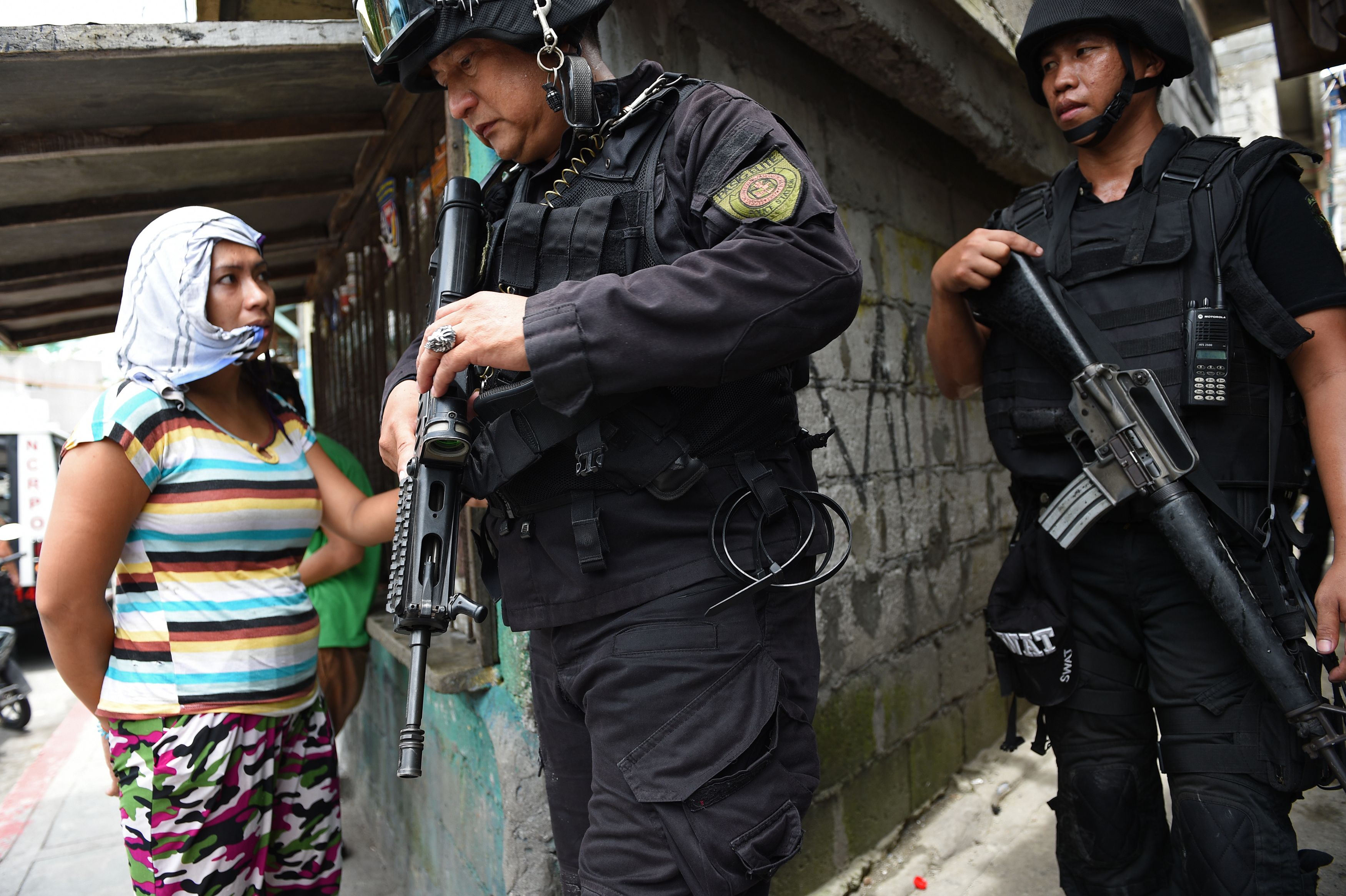 Police Special Weapons And Tactics (SWAT) personnel walk past a resident after an operation against illegal drugs in Pasig City, suburban Manila on September 5, 2016. (TED ALJIBE—AFP/Getty Images)