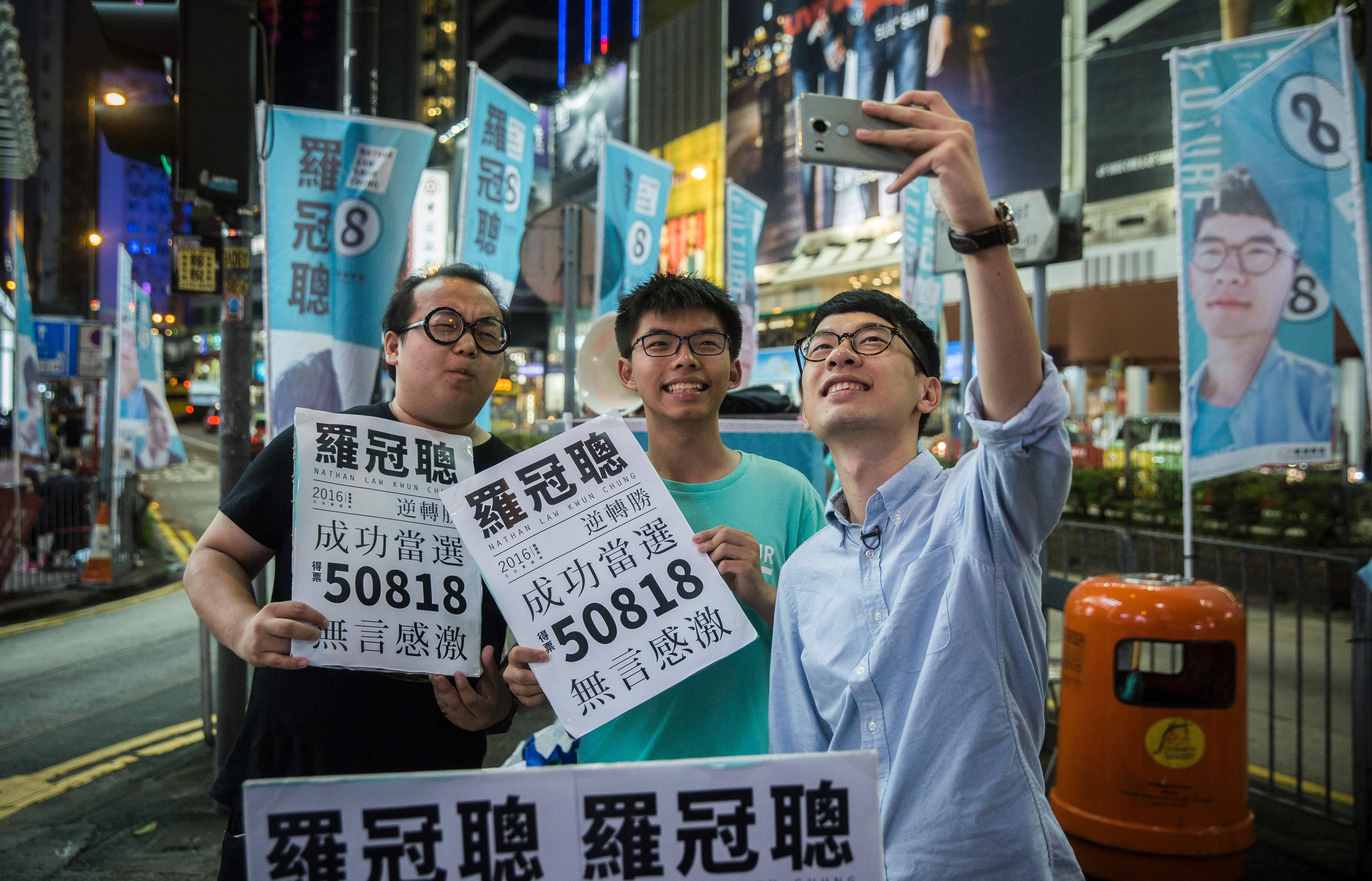 Nathan Law, right, and Joshua Wong, center, take a selfie at a rally in Causeway Bay in Hong Kong on Sept. 5, 2016, following Law's win in the Legislative Council elections (Isaac Lawrence—AFP/Getty Images)