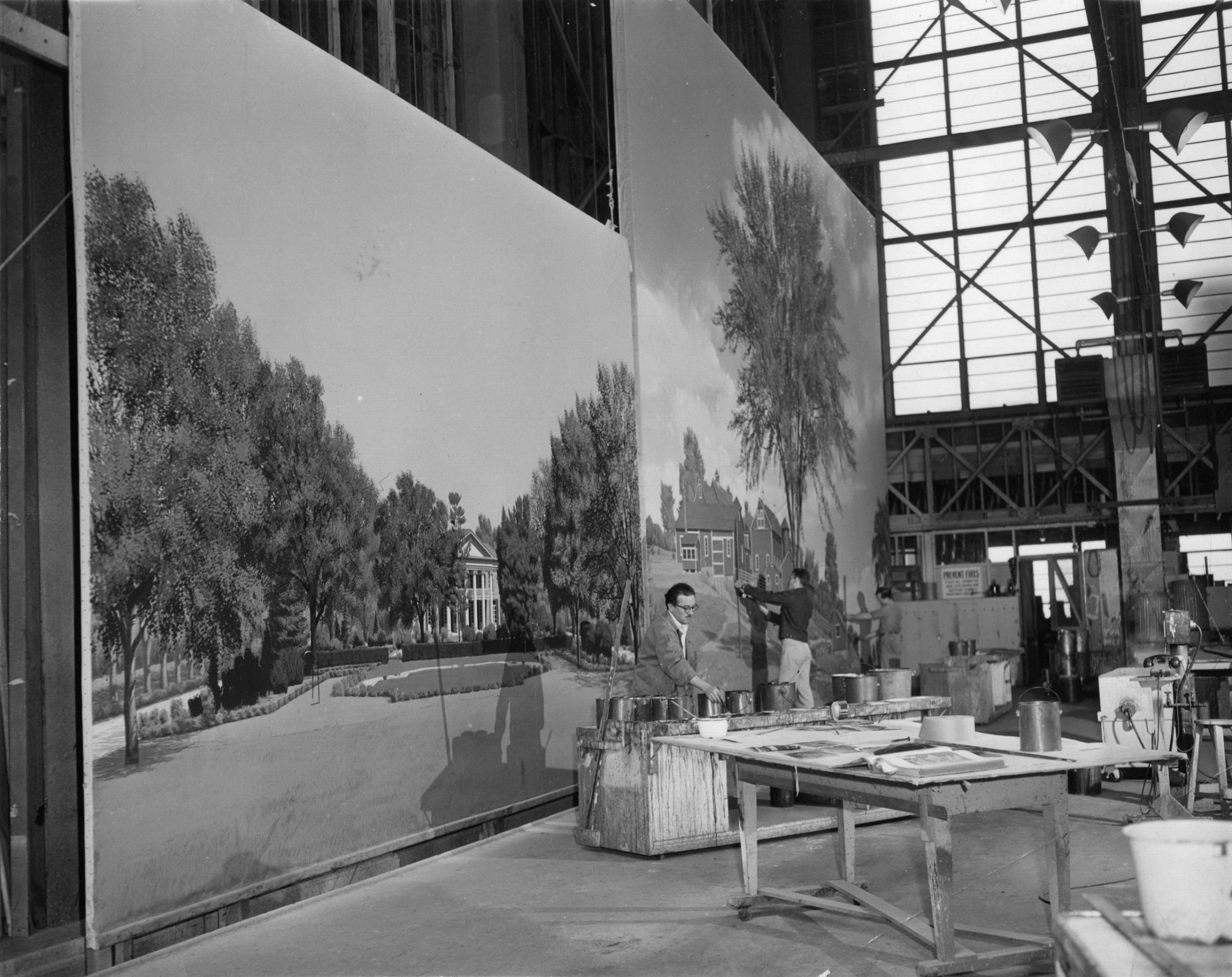 Clark Provins (left), John Harold Coakley (center), and an unknown scenic artist (right) painting at the MGM scenic art department c. 1950.
