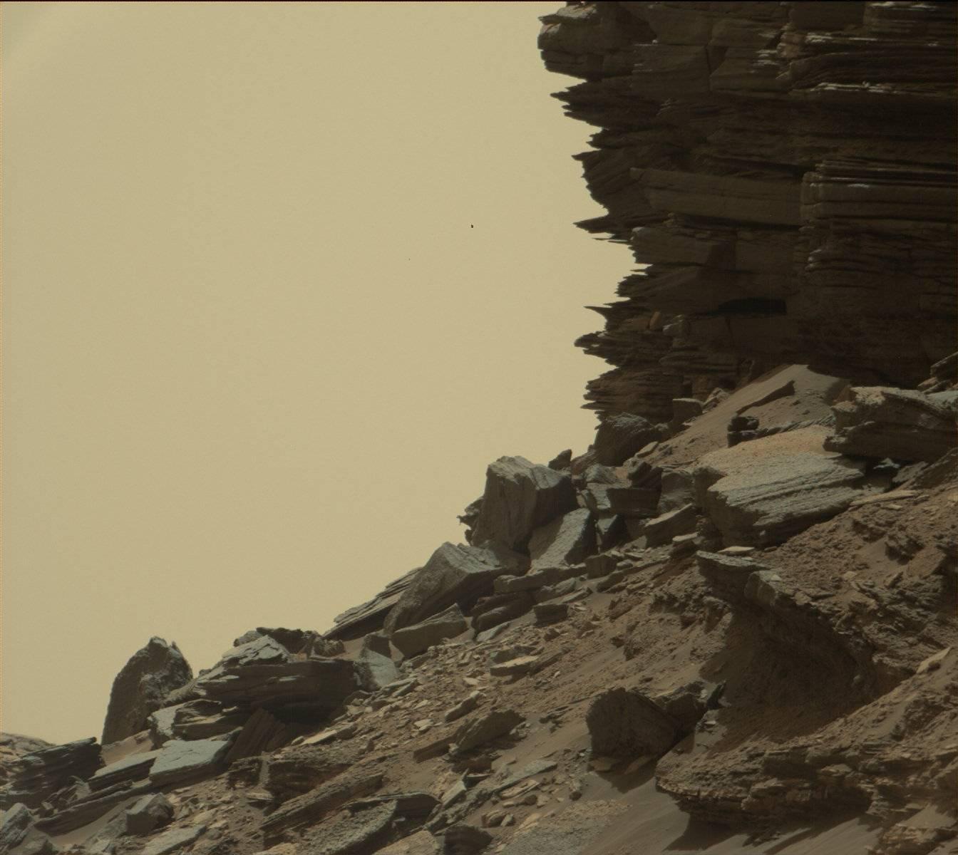 This view from Curiosity shows a dramatic hillside outcrop with sandstone layers that scientists refer to as  cross-bedding.