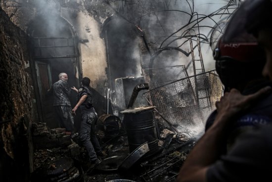 Firefighters extinguish flames following an airstrike by forces loyal to the Syrian government in the rebel-held area of Douma, on the outskirts of Damascus, on Sept. 11, 2016.