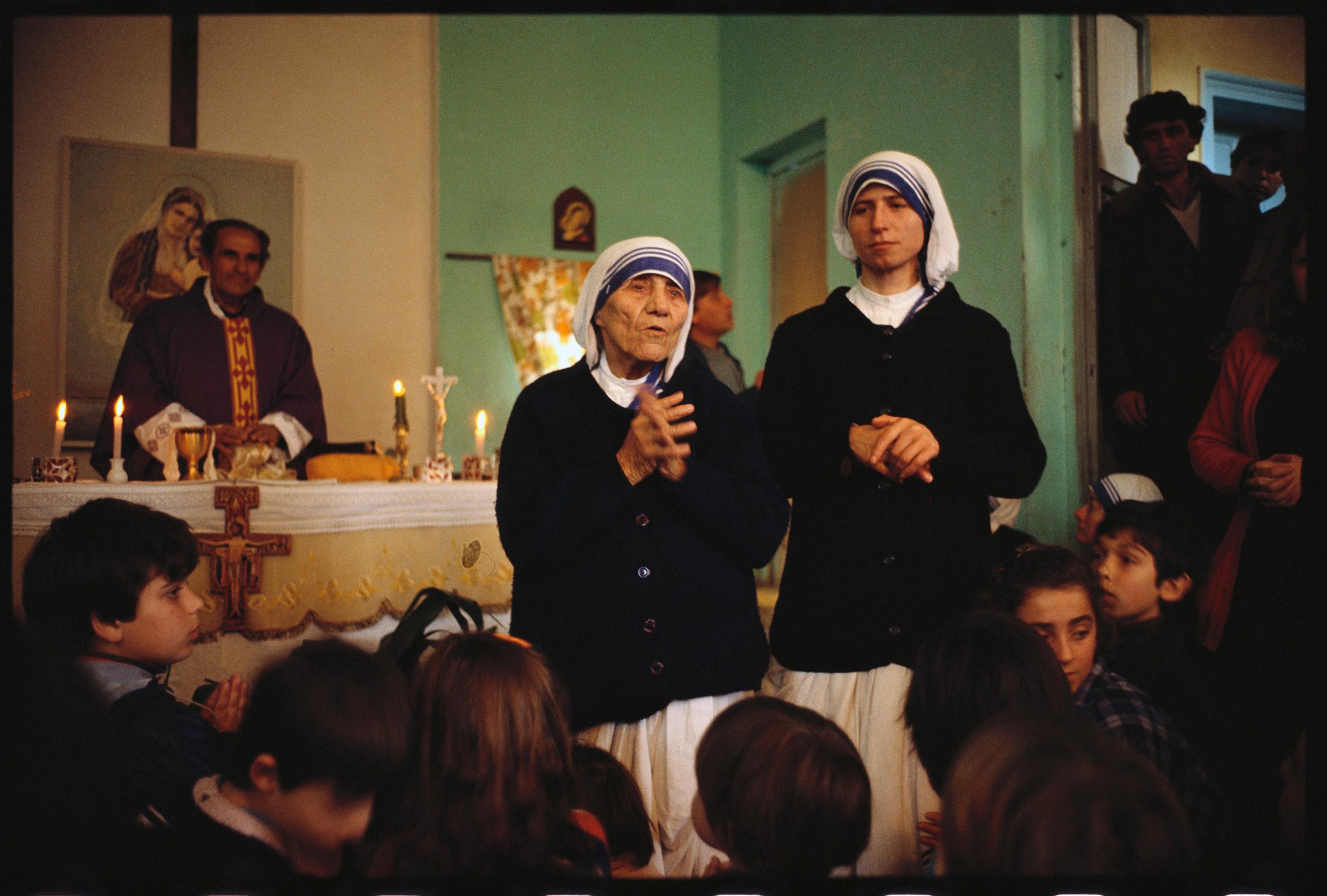 Mother Teresa addresses a group of children during mass at a church.