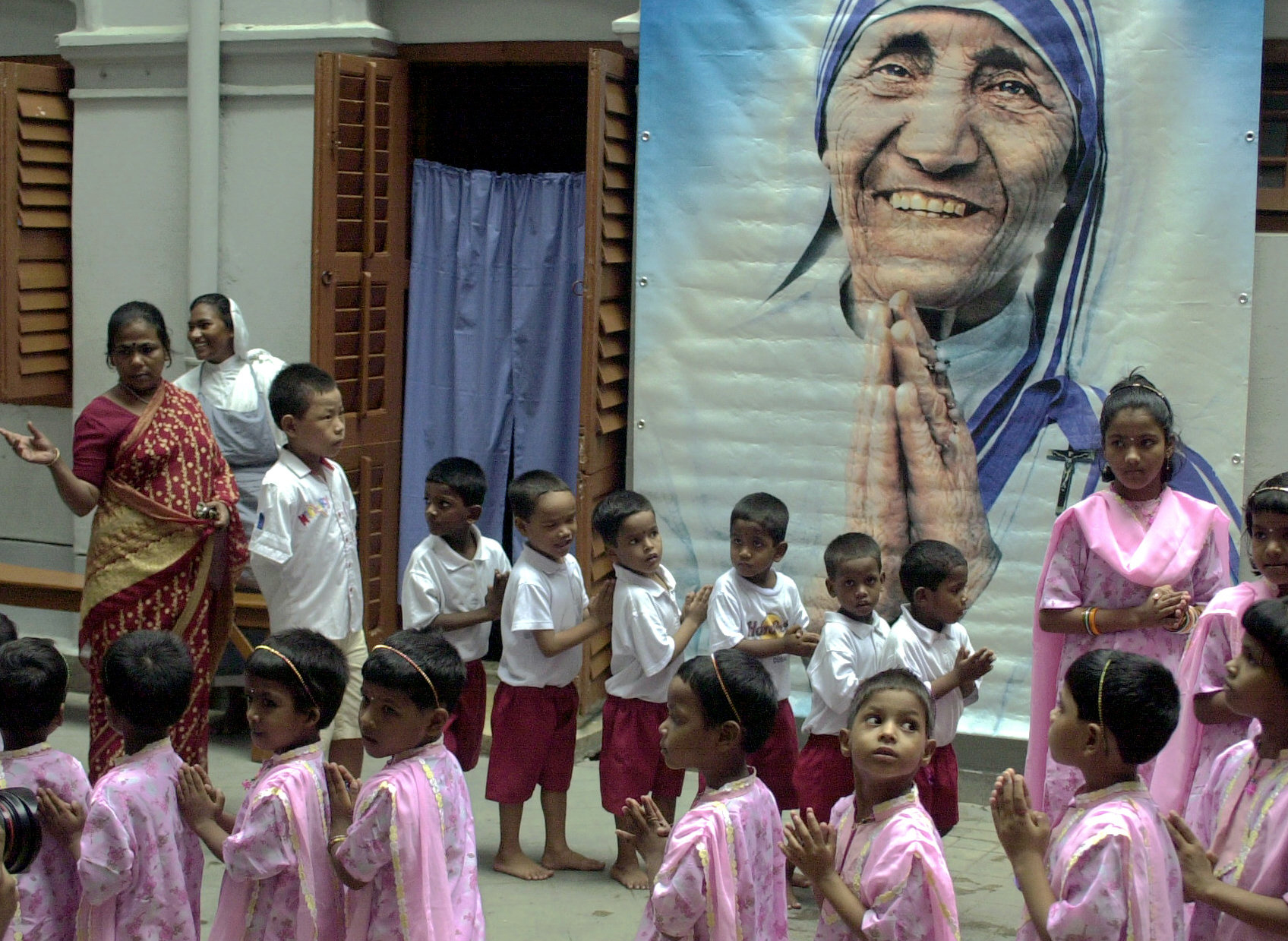 A group of Indian orphans along with a nun of the Missionaries of Charity offer prayers in front of a portrait of Mother Teresa during prayers to observe the seventh anniversary of her death in Calcutta, Sept. 5, 2004.