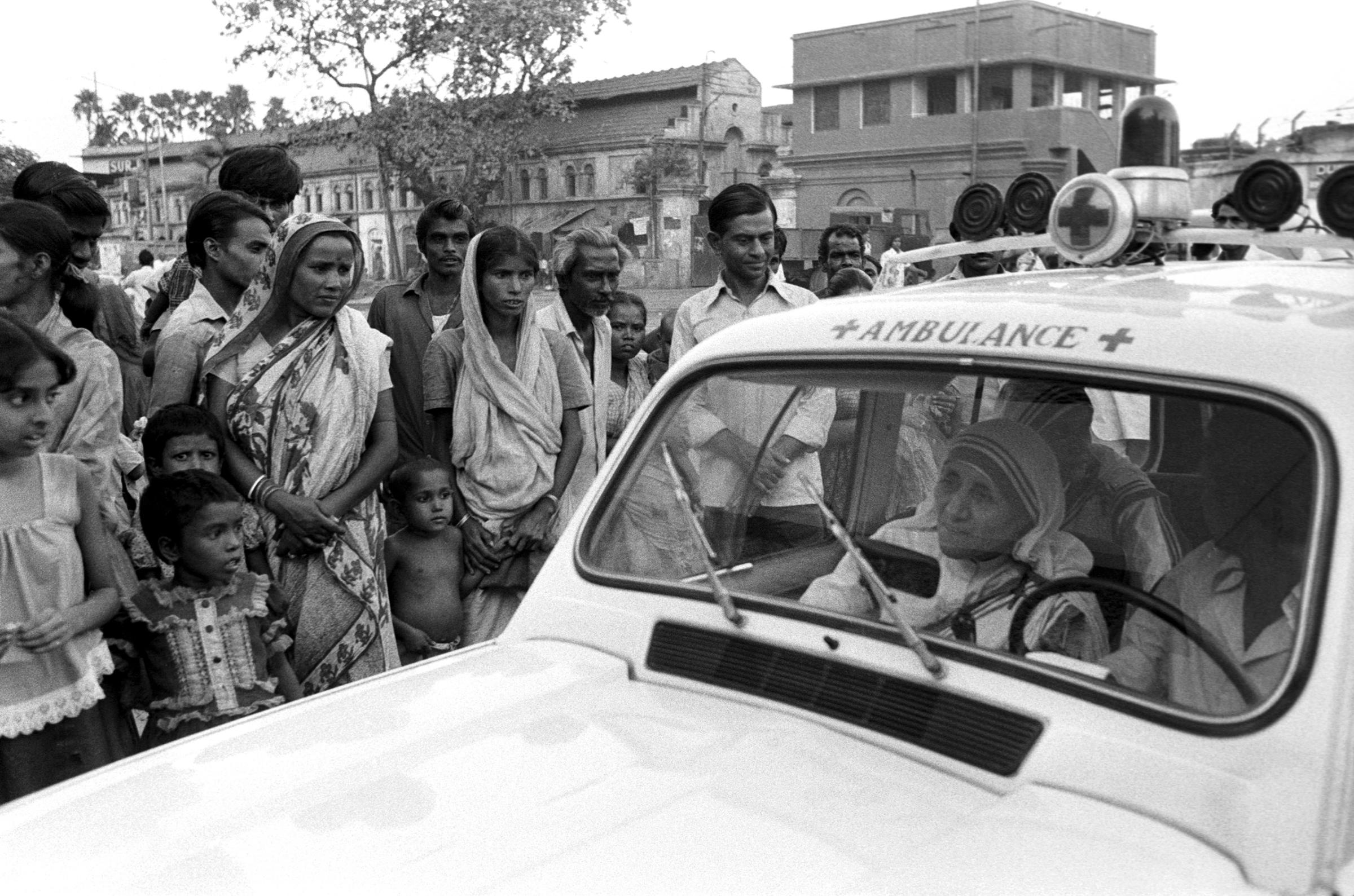 Mother Teresa rides in an ambulance alongside a group of impoverished people in Calcutta, India, in October 1979.