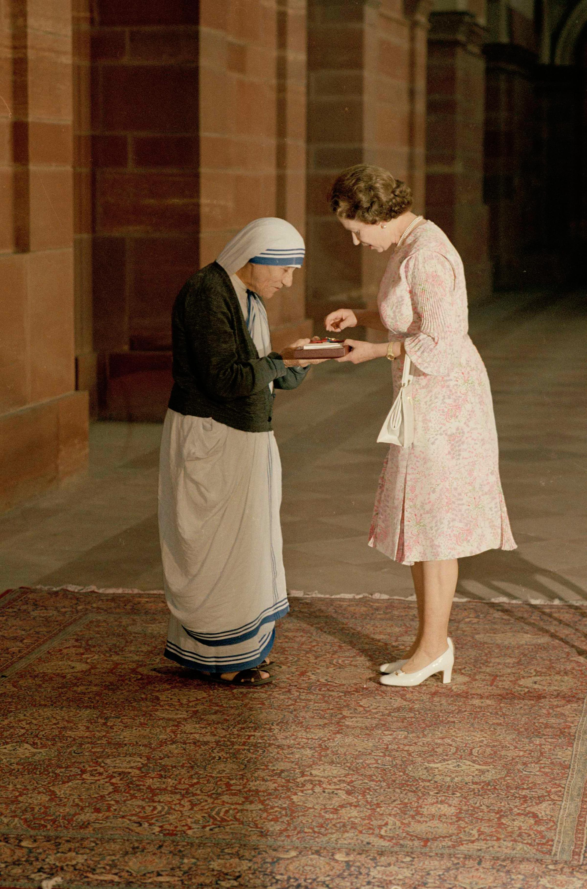 Queen Elizabeth II and Mother Teresa look at the Insignia of the Honorary Order of Merit, which she just presented to the Lady of Calcutta, at the Rashtrapati Shavar in New Delhi, India, on Nov. 24, 1983.