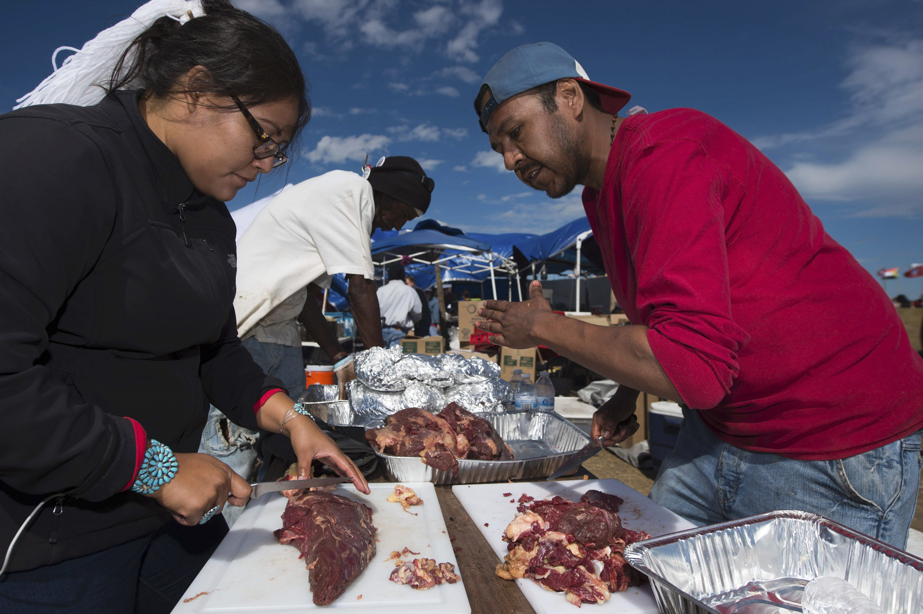 Lamar Armstrong of the Mojave Paiute, right,  instructs graduate student Tyesha Ignacio of the Najavo Nation how to prepare donated bison meat in the main kitchen area of the Standing Rock Sioux protest encampment near Cannon Ball, North Dakota ,on Sept. 3, 2016.