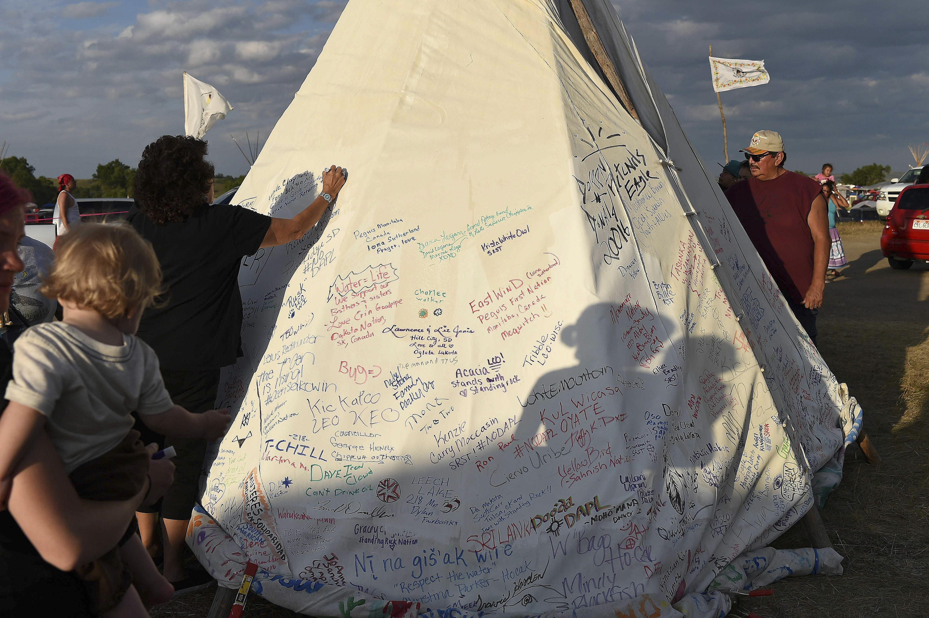 People sign a teepee with words of support for protestors at an encampment where hundreds of people gathered to join the Standing Rock Sioux Tribe's protest against the construction of the Dakota Access Pipe (DAPL), near Cannon Ball, North Dakota, on Sept. 3, 2016.