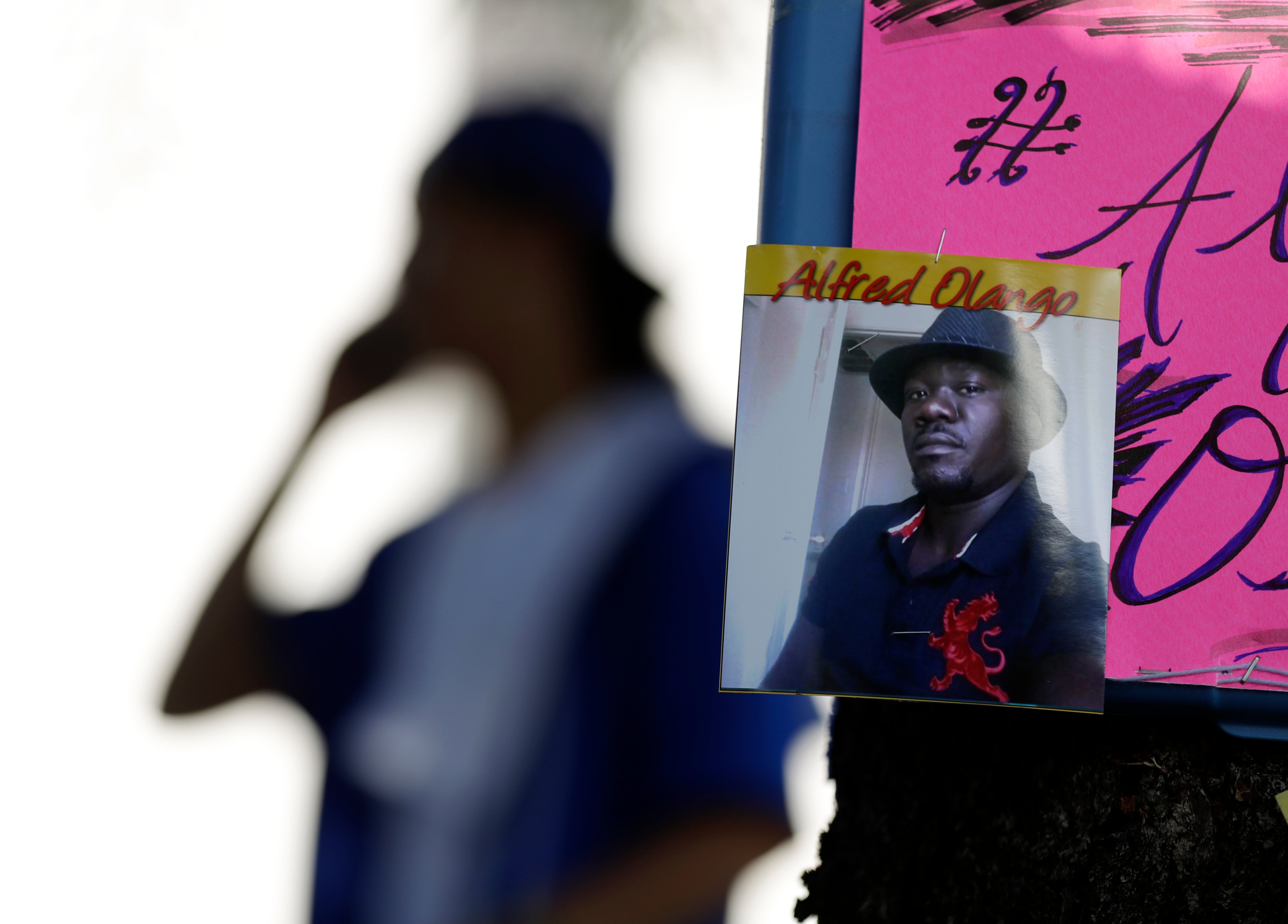 A man stands behind a picture of Alfred Olango during a protest, in El Cajon, Calif., on Sept. 28, 2016. (Gregory Bull—AP)