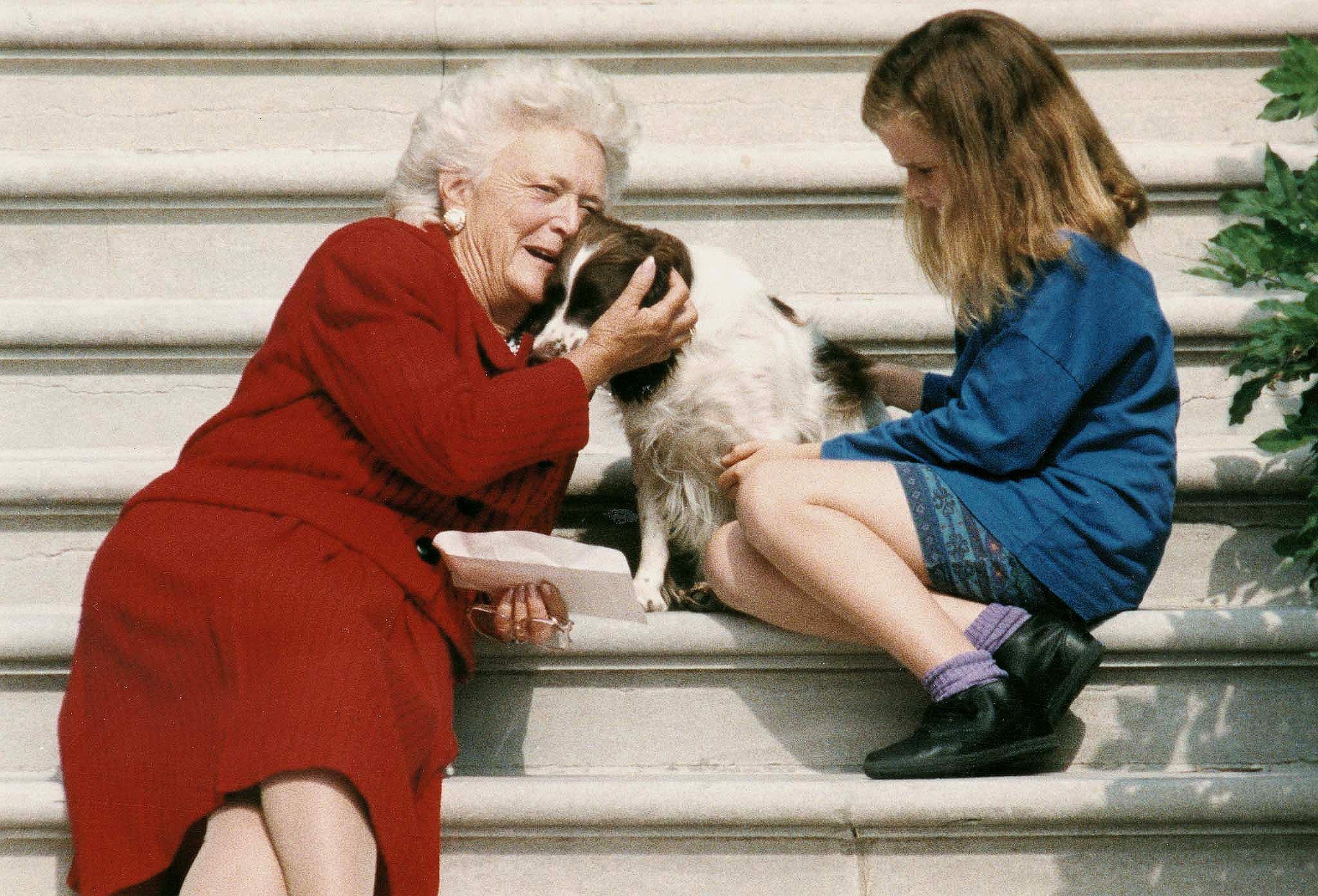 Barbara Bush talks to her dog, Millie, as she and granddaughter, Barbara Bush, age nine, wait for George Bush to return to the White House on Sept. 13, 1991,