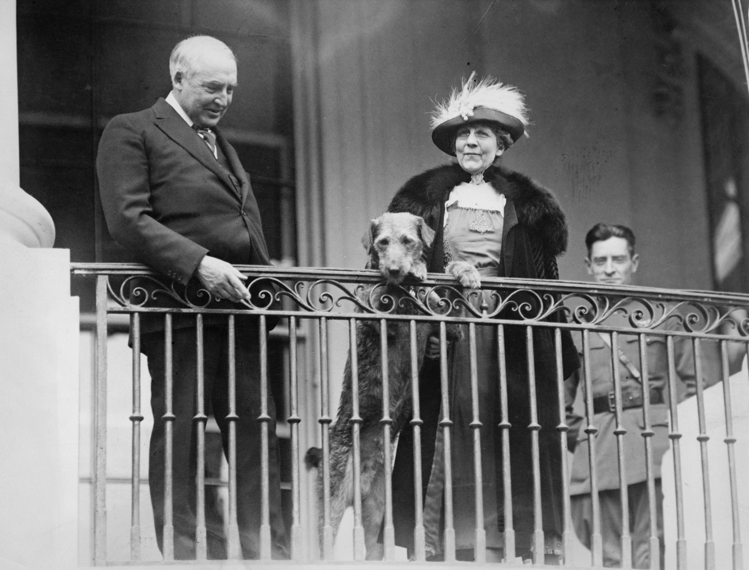 Warren G. Harding, Florence Harding, and their dog, Laddie Boy, watch from a balcony as an annual Easter Monday children's egg-rolling event takes place on the White House lawn, circa 1922.