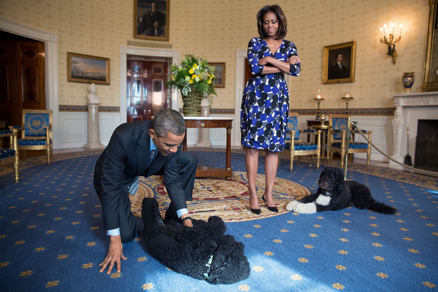 Barack Obama and Michelle Obama, joined by family pets Sunny and Bo, wait to greet visitors in the Blue Room during a White House tour, Nov. 5, 2013.