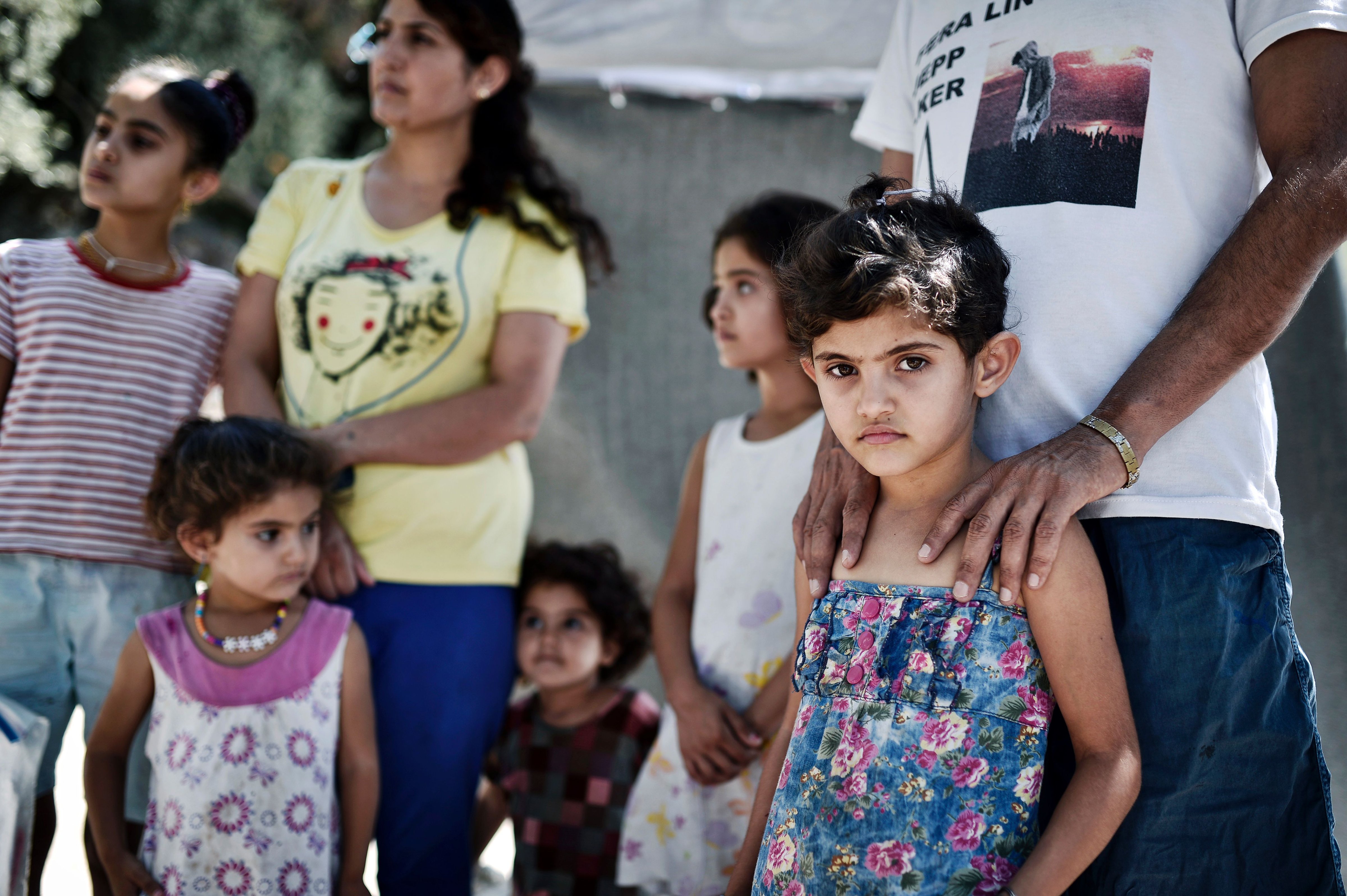Ando Elias Tareq, a Yezidi from Sinjar in Iraq, stands behind his daughter outside the Samos hotspot where they live on Sept. 1, 2016. (Louisa Gouliamaki—AFP/Getty Images)