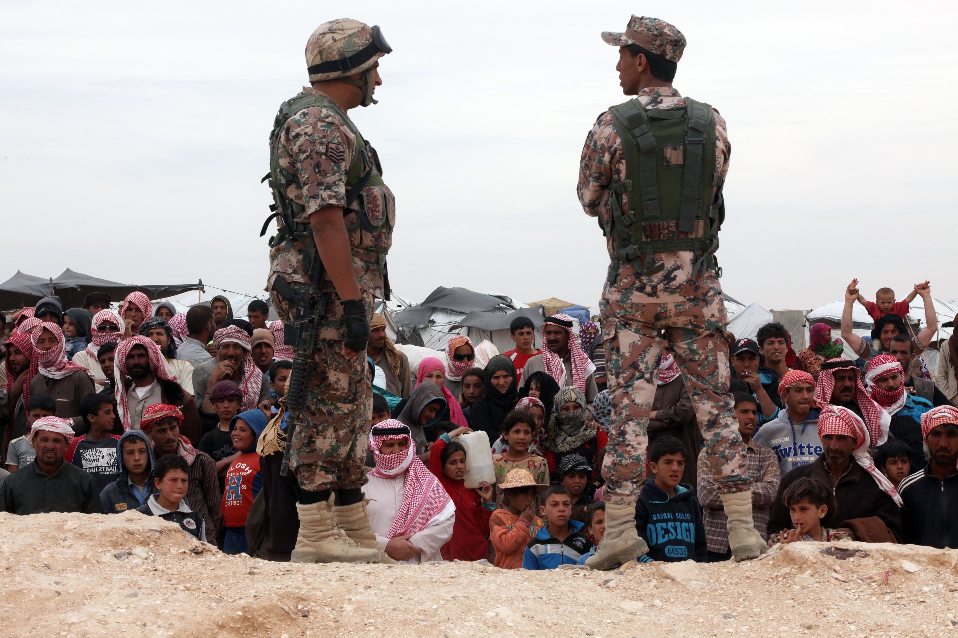 Soldiers stand near Syrian refugees who have arrived at the Jordanian military crossing point of Hadalat at the border with Syria after a long walk through the Syrian desert in Hadalat, Jordan, on May 4, 2016. (Jordan Pix—Getty Images)