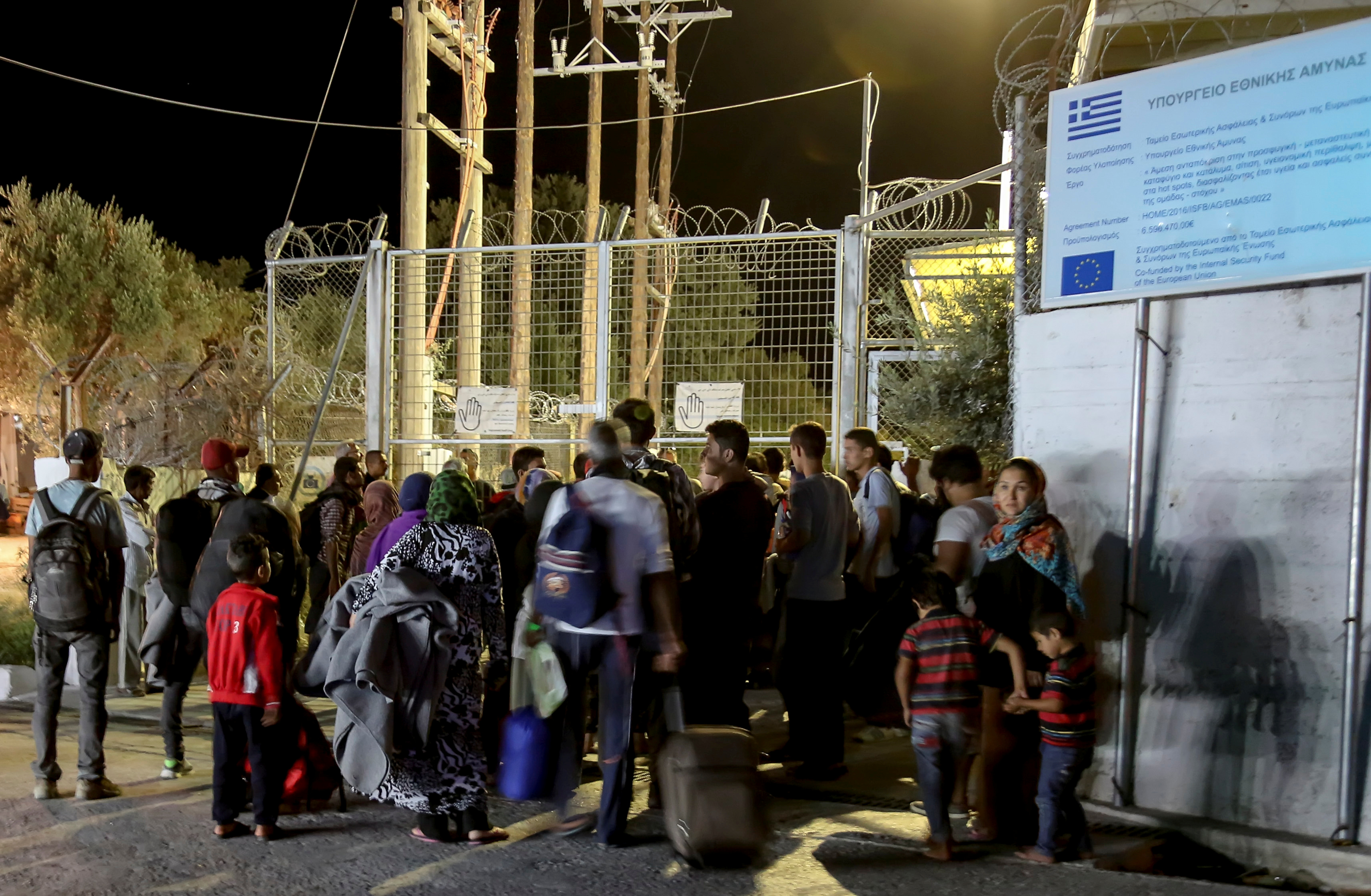 Refugees and migrants stand at the closed gate of the Moria migrant camp, after a fire at the facility, on the island of Lesbos, Greece, Sept. 19, 2016. (Manolis Lagoutaris—Intime/Reuters)