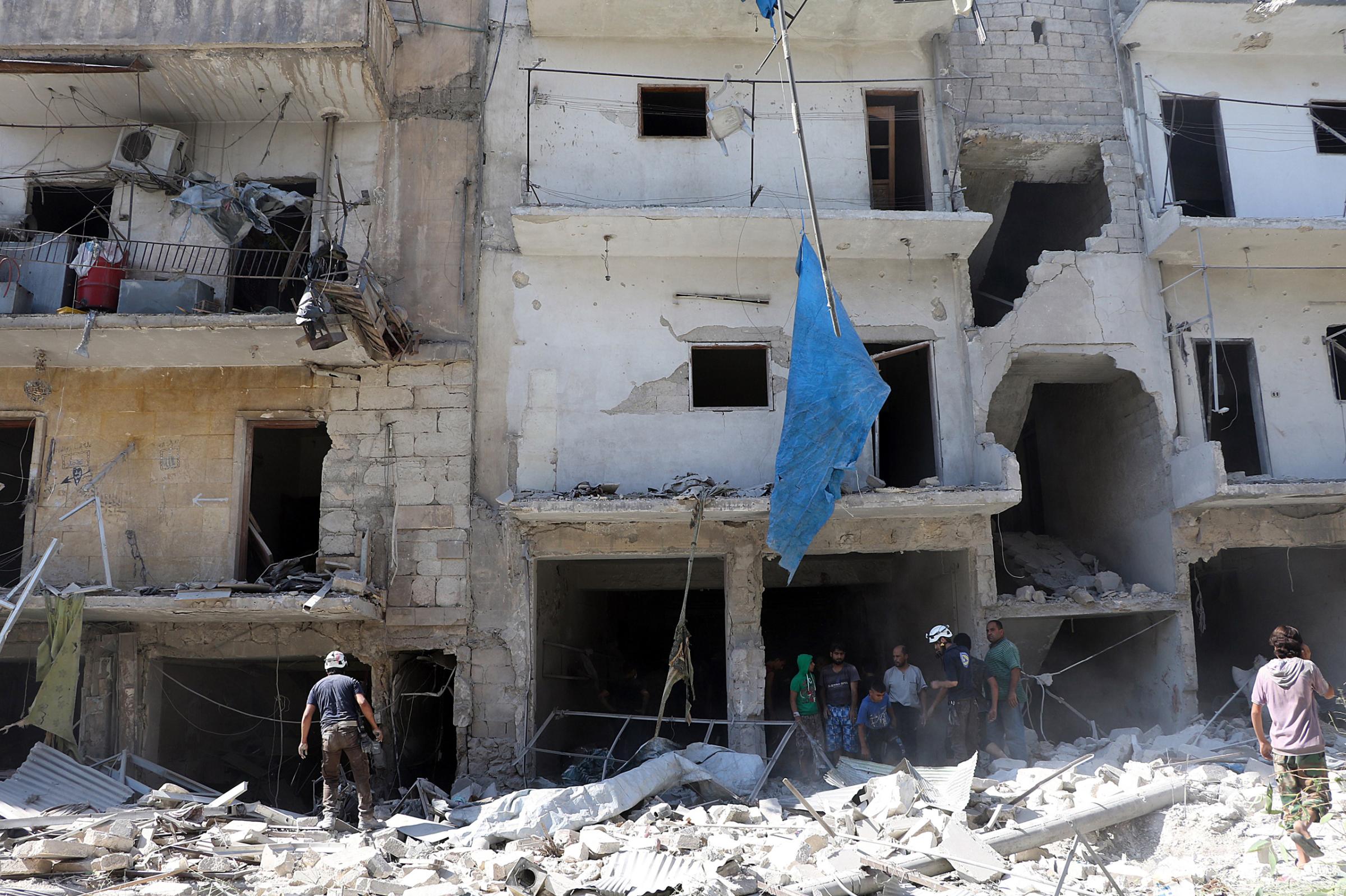 Search and rescue team members inspect the debris of buildings after Russian army aircrafts hit residential areas in the Sukari district of Aleppo, Syria, on Sept. 7, 2016.