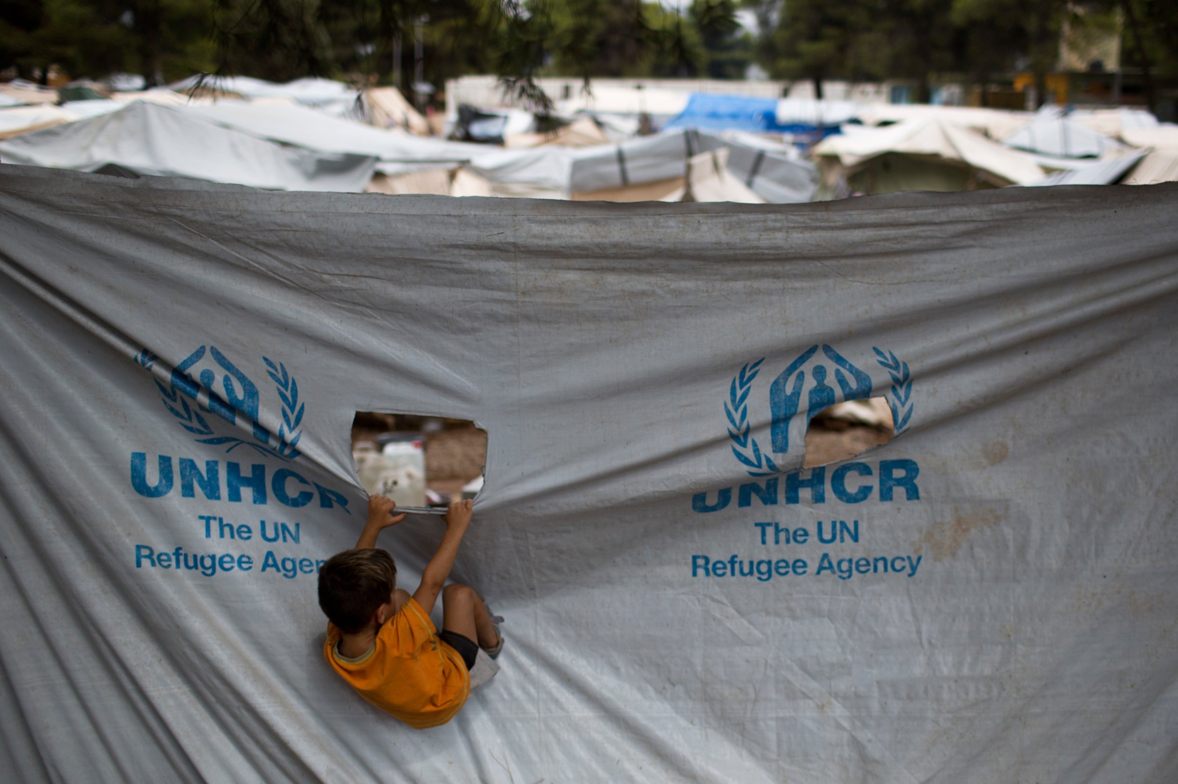 A child play in front of a UNHCR plastic sheet at Ritsona refugee camp, north of Athens, which hosts about 600 refugees and migrants on Thursday, Sept. 8, 2016. The refugee crisis is expected to be a central issue in discussions Friday at a meeting in Athens of leaders from Mediterranean countries in the European Union. (AP Photo/Petros Giannakouris)