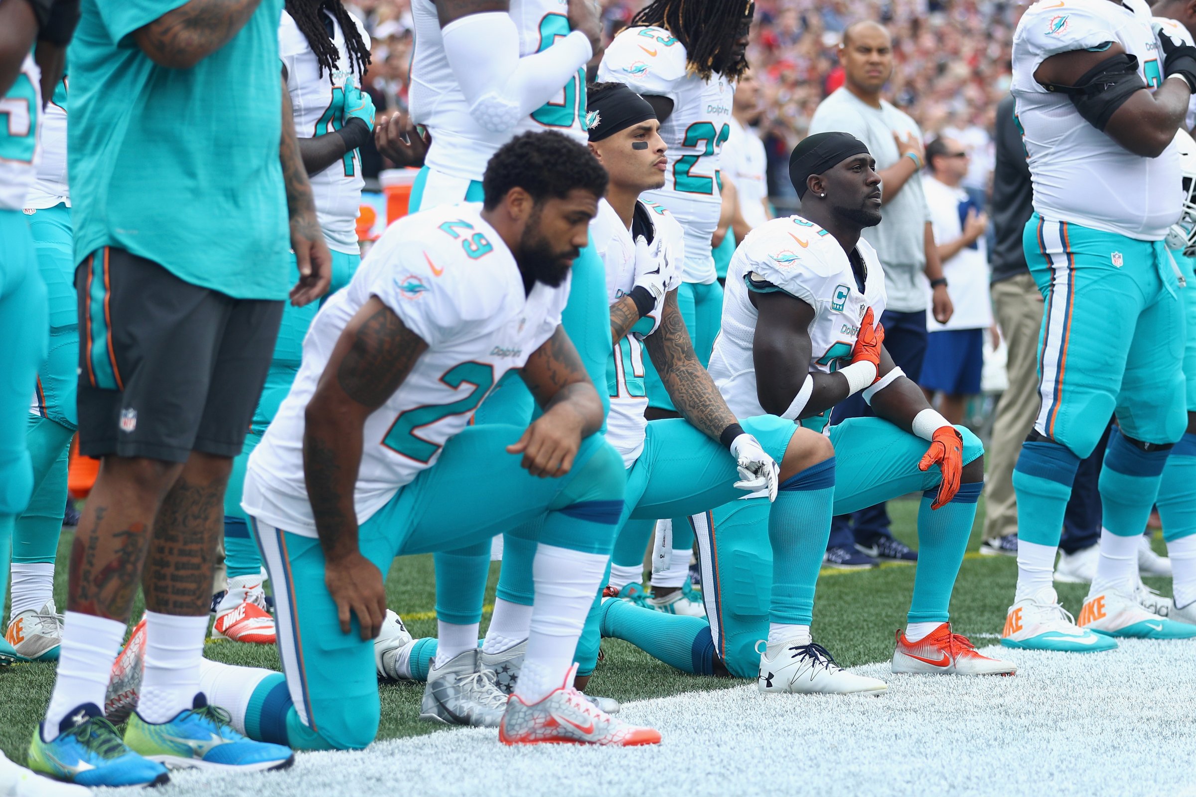 (L-R) Arian Foster #29, Kenny Stills #10 and Michael Thomas #31 of the Miami Dolphins kneel during the national anthem before the game against the New England Patriots at Gillette Stadium in Foxboro, Mass., on Sept. 18, 2016.