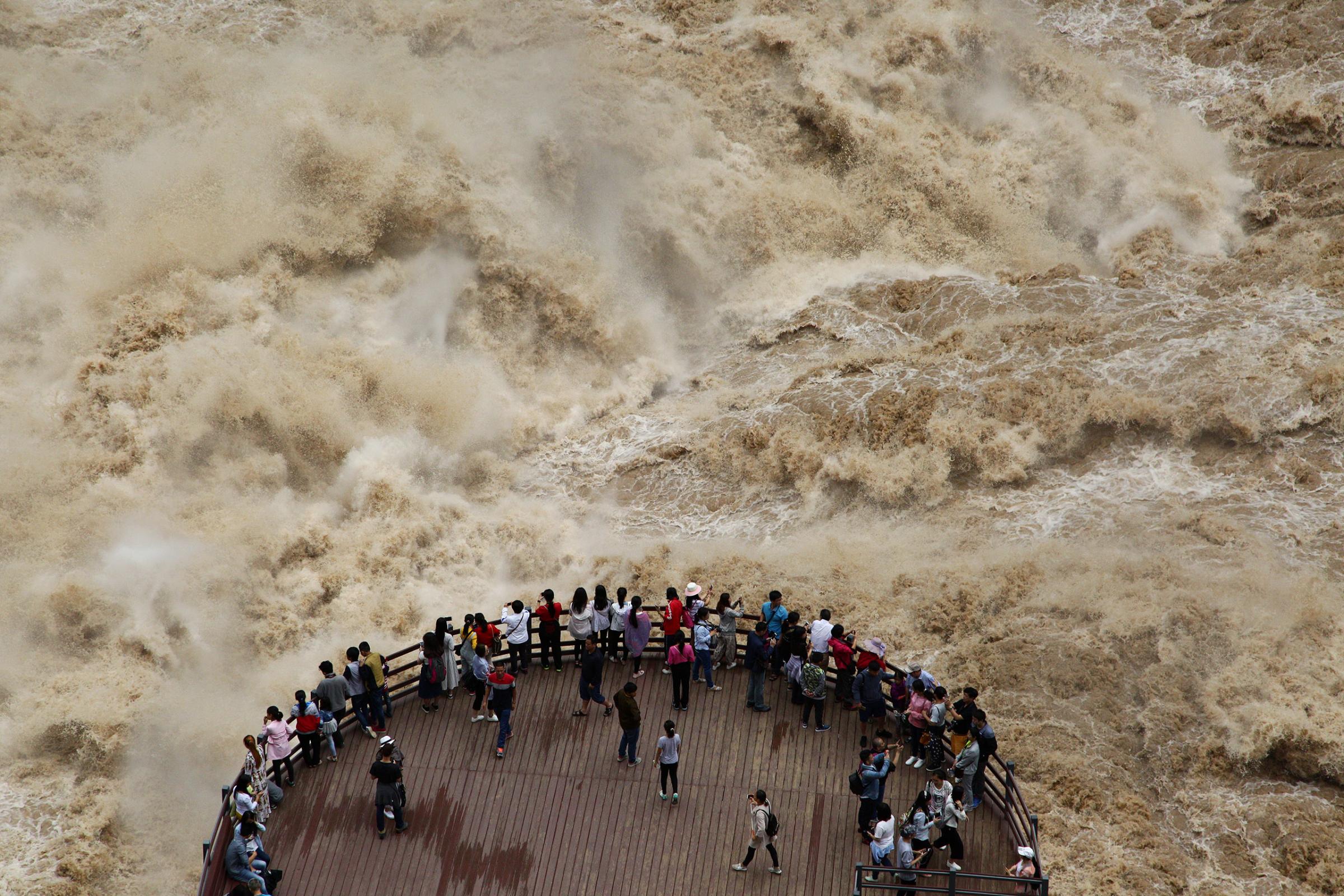 People watch the flooded Jinsha River at a sightseeing platform in Tiger Leaping Gorge, in Diqing, Yunnan Province, China, July 15, 2016.