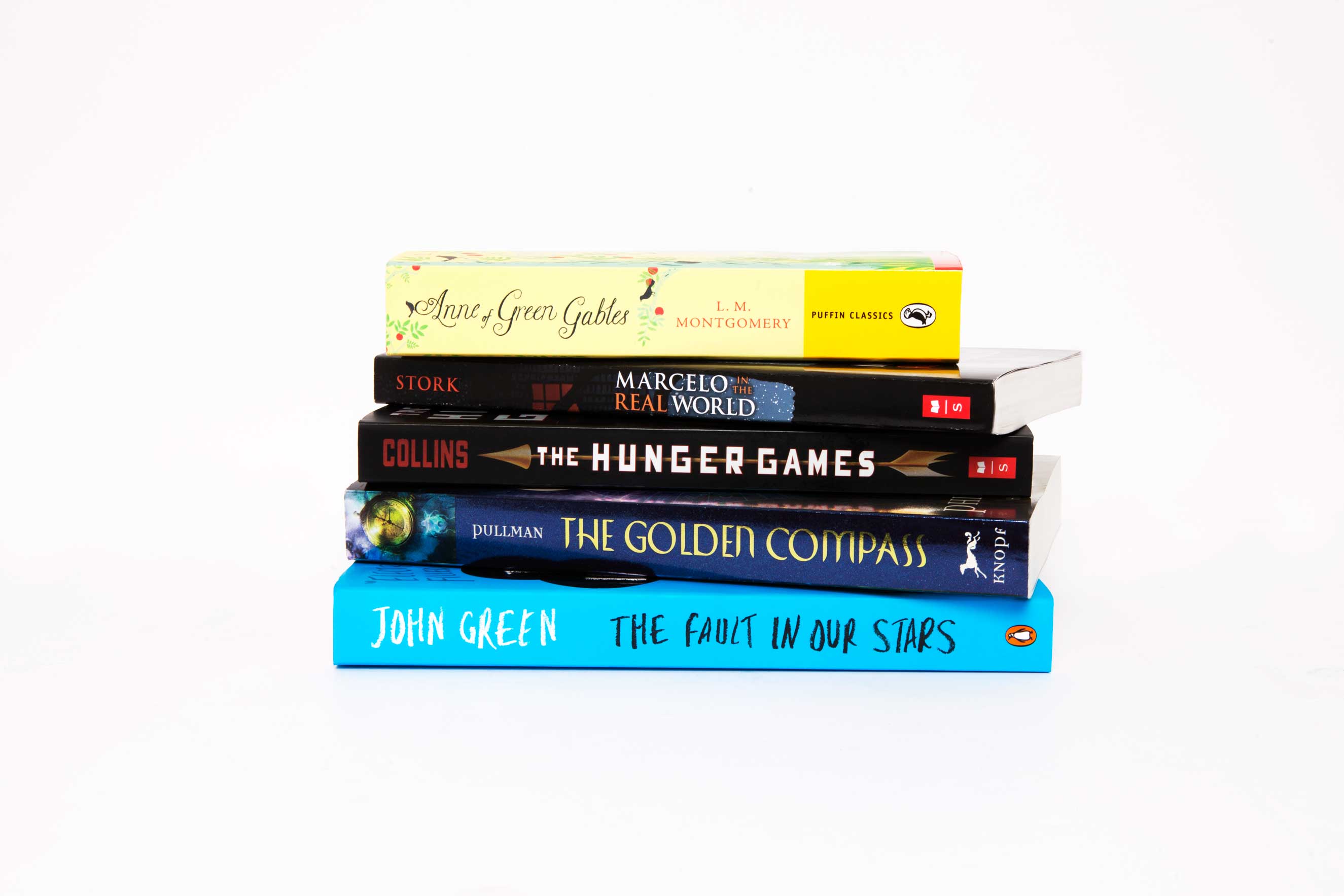 Photo of a stack of Young Adult books. (Top to bottom): Anne of Green Gables by L. M. Montgomery, Marcelo in the Real World by Francisco X. Stork, The Hunger Games by Suzanne Collins, The Golden Compass by Philip Pullman and The Fault in Our Stars by John Green. (No Credit)