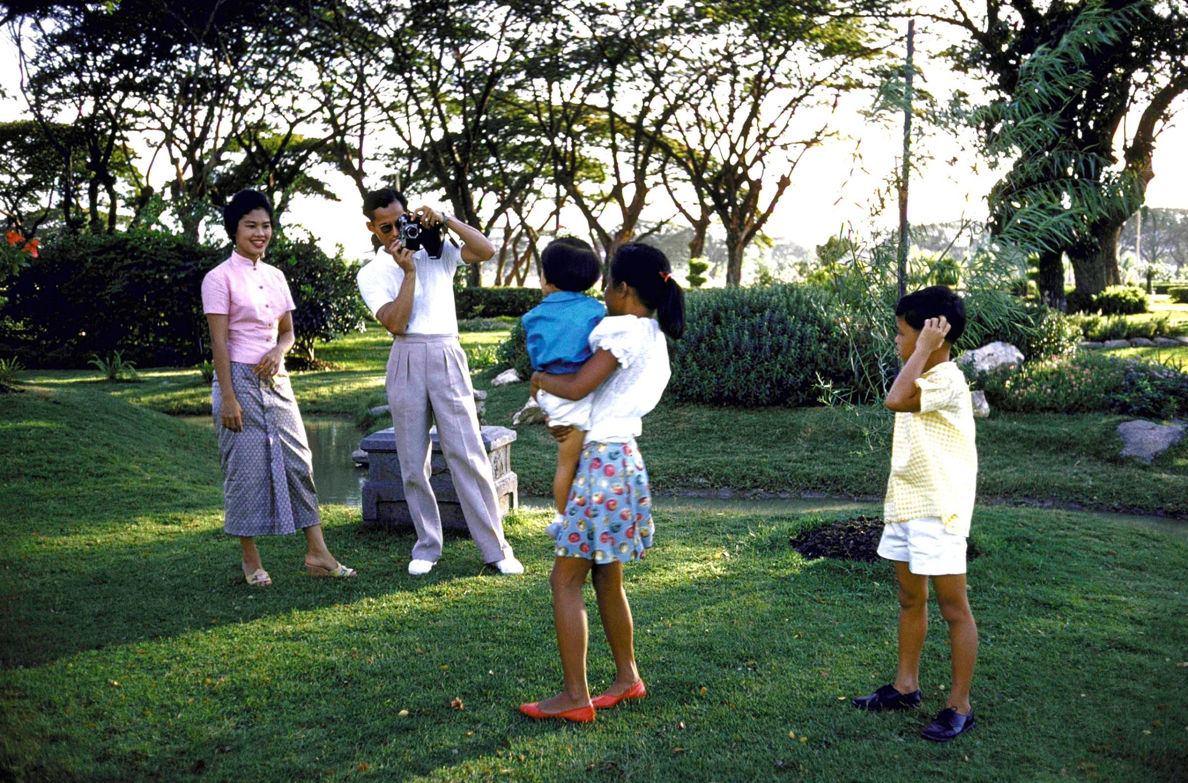 Thailand's King Bhumibol Adulyadej (2L) and Queen Sirikit (L) taking pictures of their children Ubolratana (C), Chulabkorn (in sister's arms) and Vajiralongkorn on palace grounds, 1960.