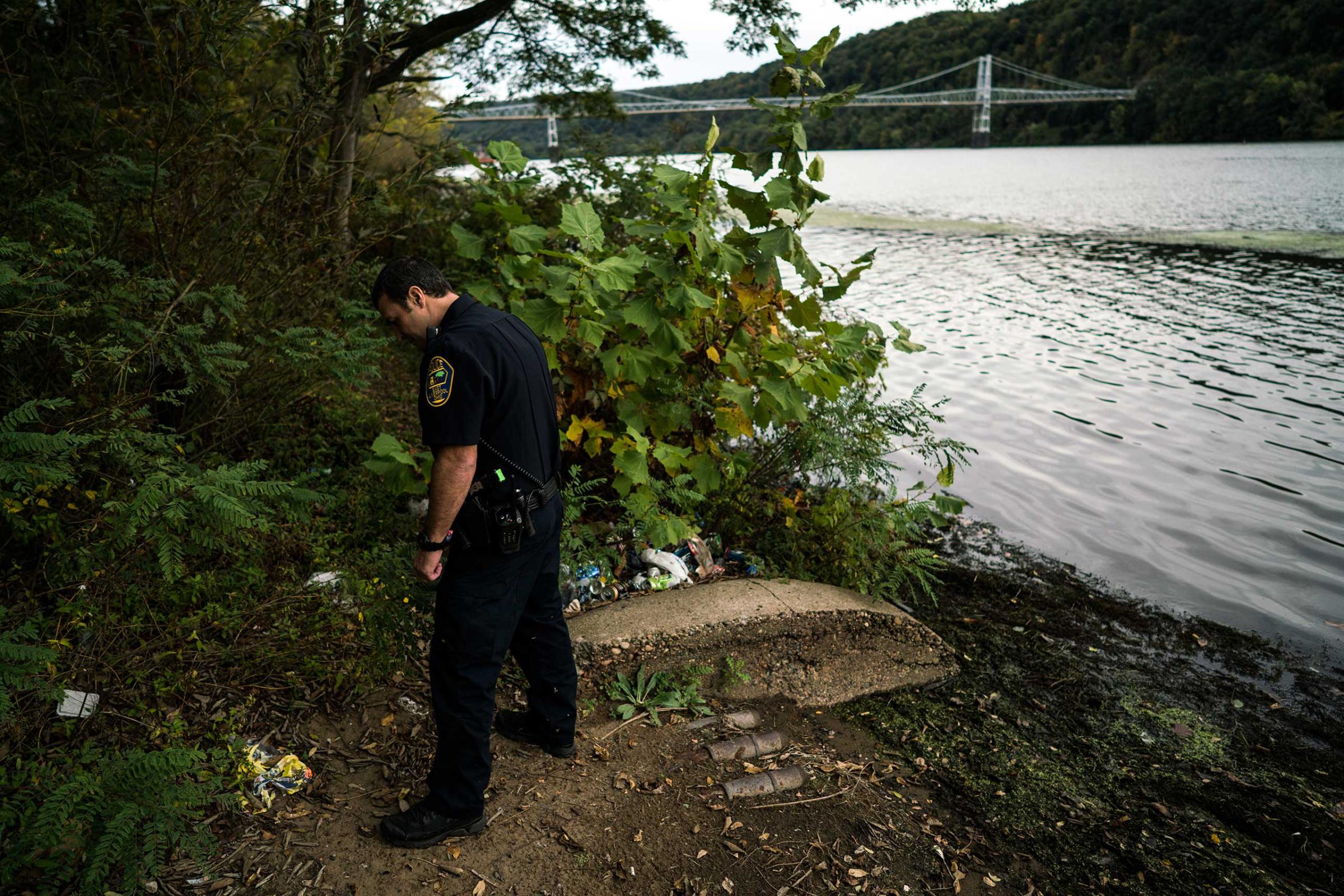 A patrolman searches for syringes and abandoned drug paraphernalia along the shore of the Ohio River in East Liverpool, Ohio, on Oct. 8, 2016.