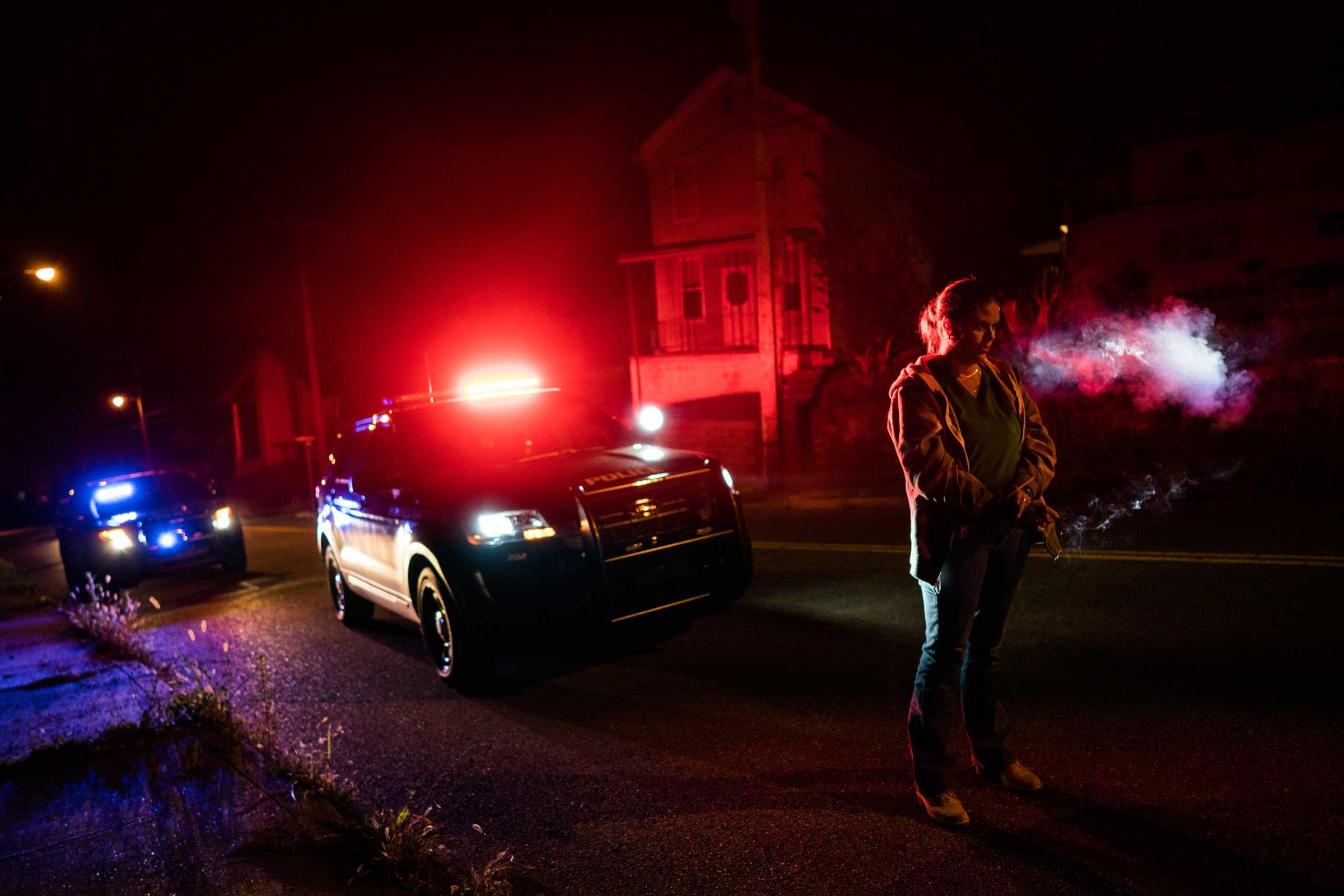 A suspect stopped by police smokes a cigarette, as his car is searched for drugs, in East Liverpool, Ohio, on Oct. 8, 2016.