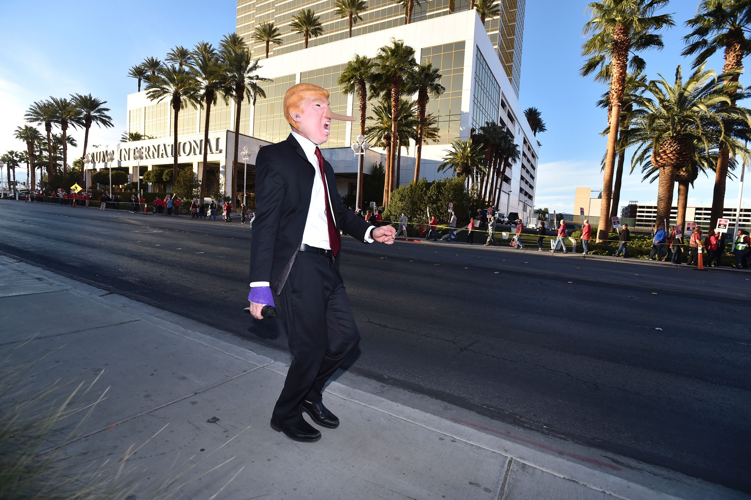 Gil Mobley wears a Donald Trump costume while singing a song about him as protesters rally in front of the Trump Hotel in Las Vegas on Feb. 23, 2016.
