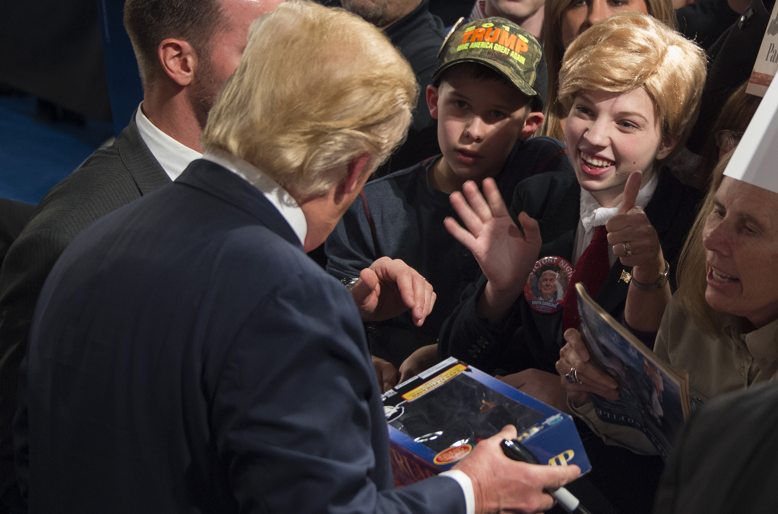 Donald Trump signs a Trump doll for a girl dressed in costume like him during a campaign rally in Sumter, S.C., on Feb. 17, 2016.
